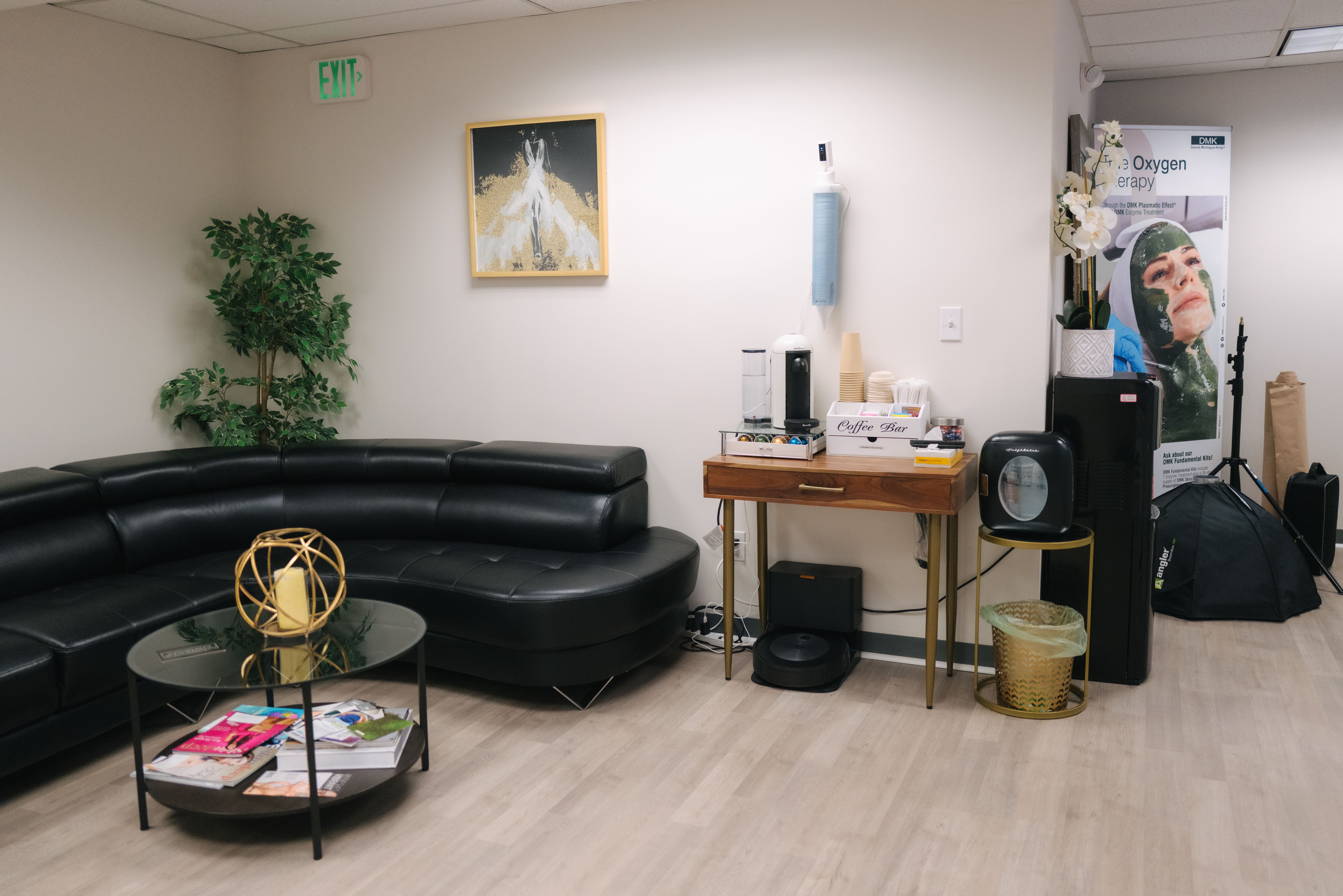 Beauty Republic waiting area with a black sofa, glass coffee table, and coffee station.