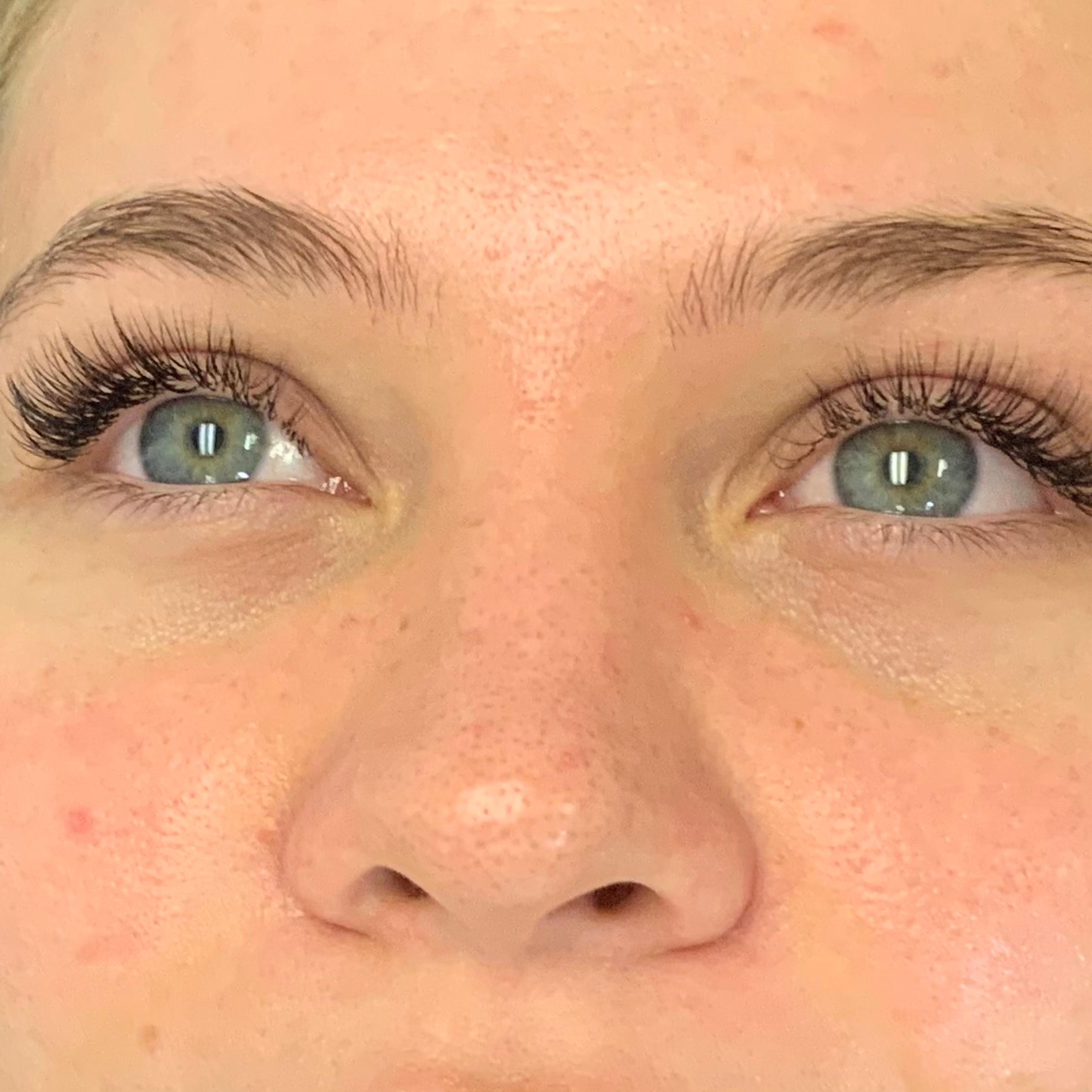 Young woman with long eyelashes and flushed face, lying down and looking up.