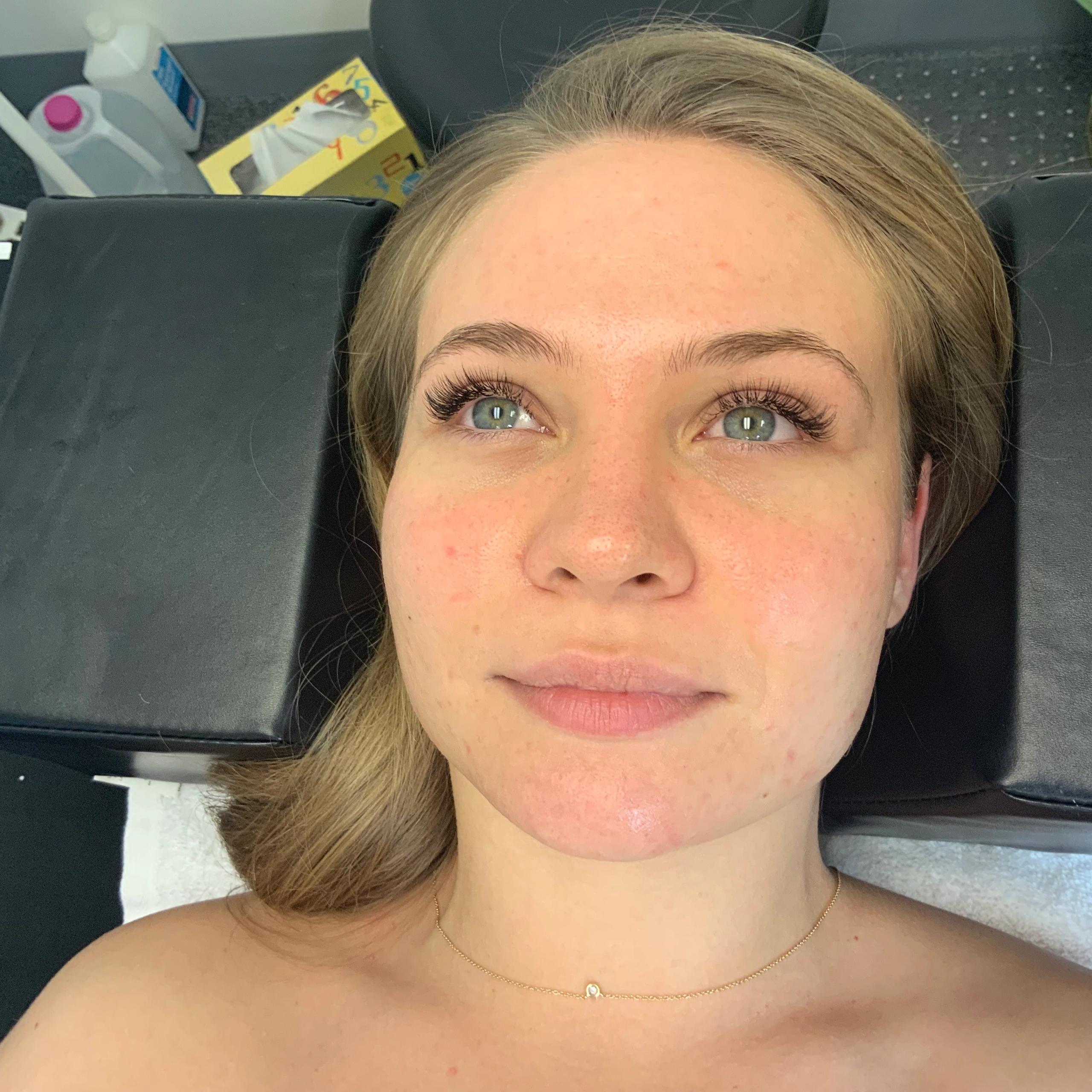 Young woman with long eyelashes and flushed face, lying down and looking up.