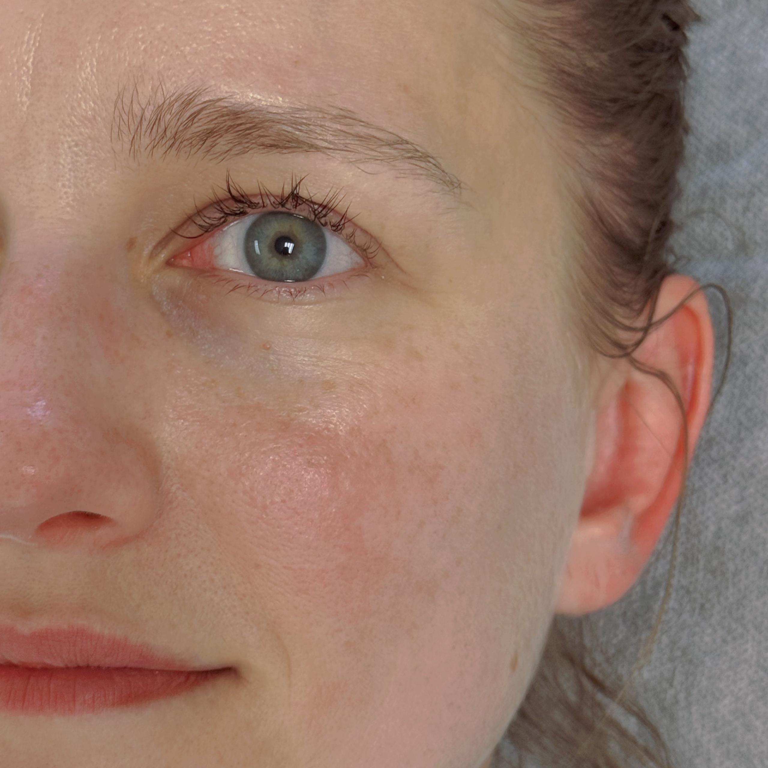 Close-up of a woman's right eye and a faint smile