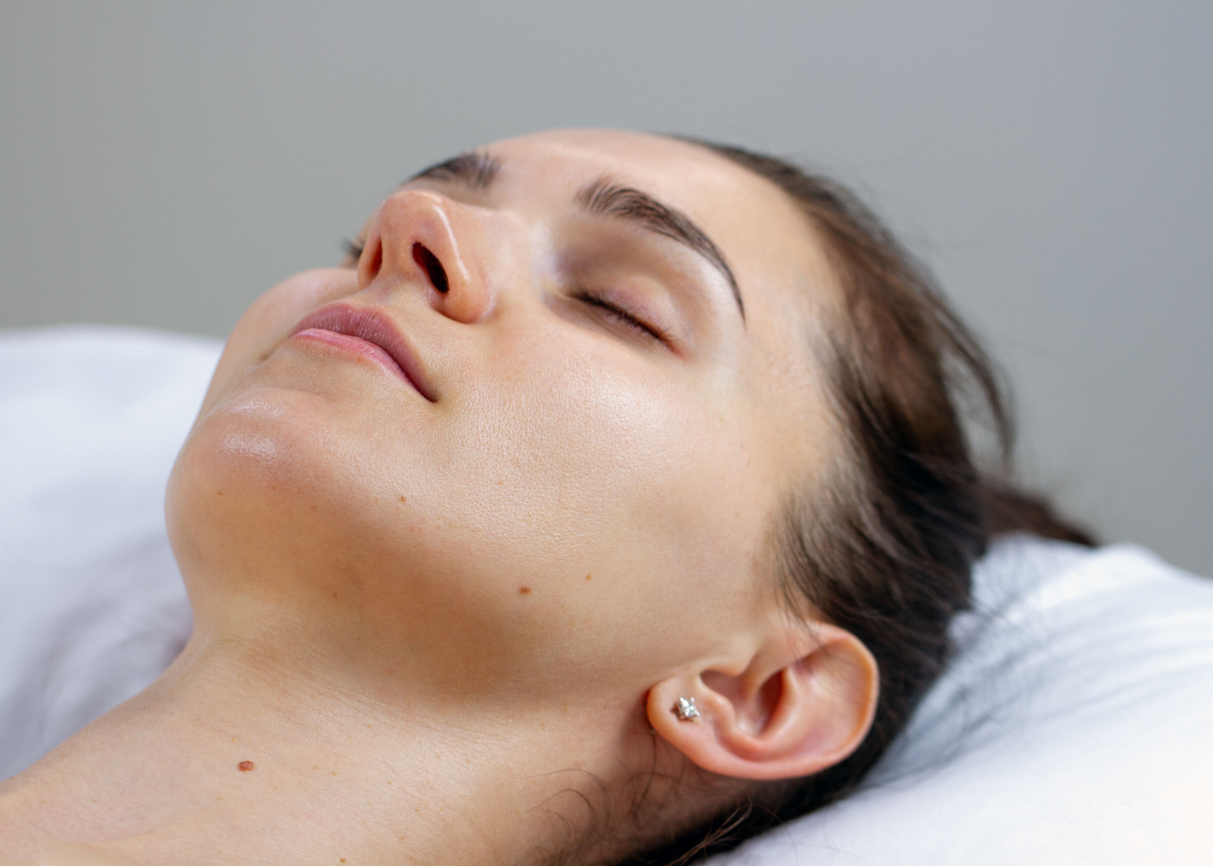 Close-up of a woman with a clean skin and eyes closed looking relaxed.