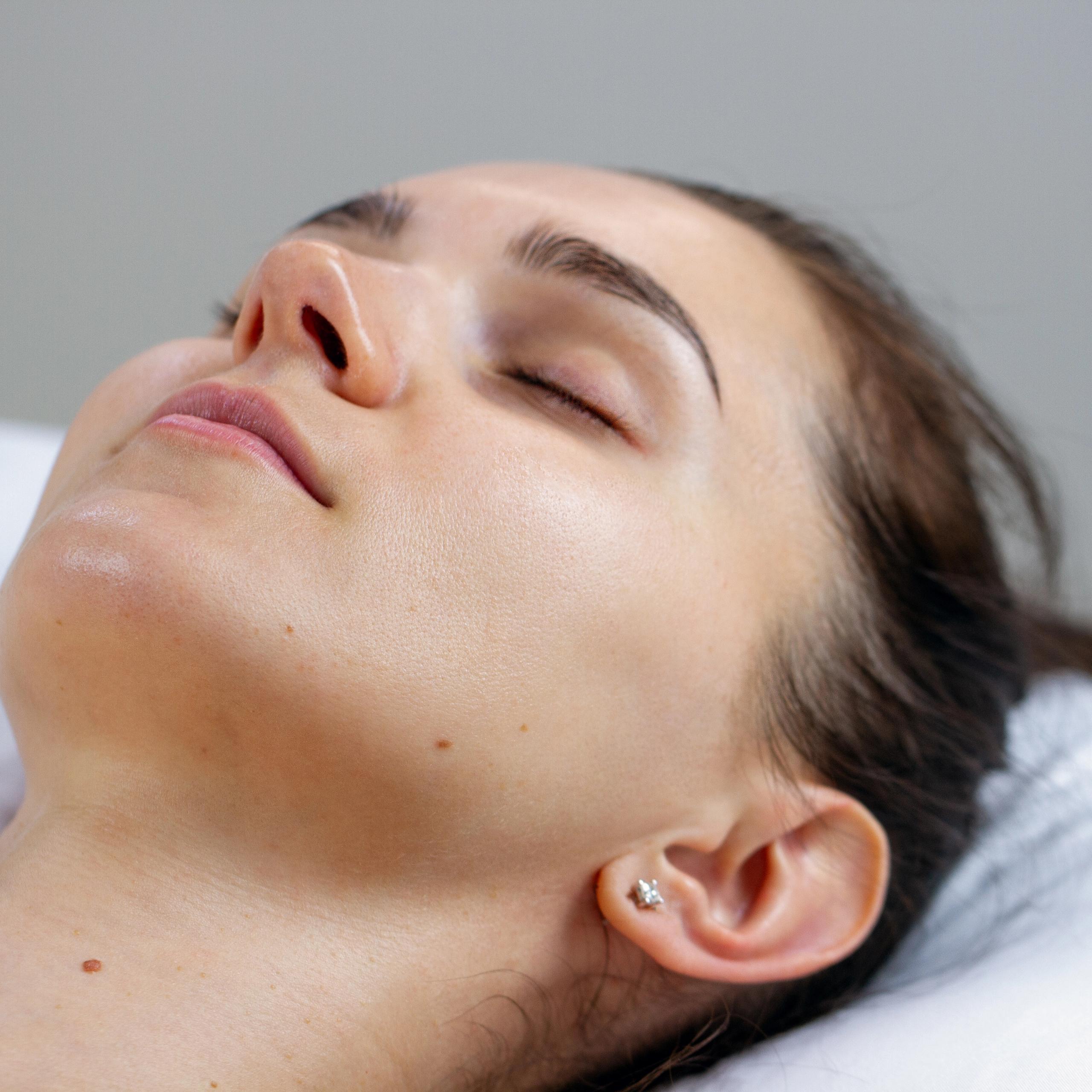 Close-up of a woman with a clean skin and eyes closed looking relaxed.
