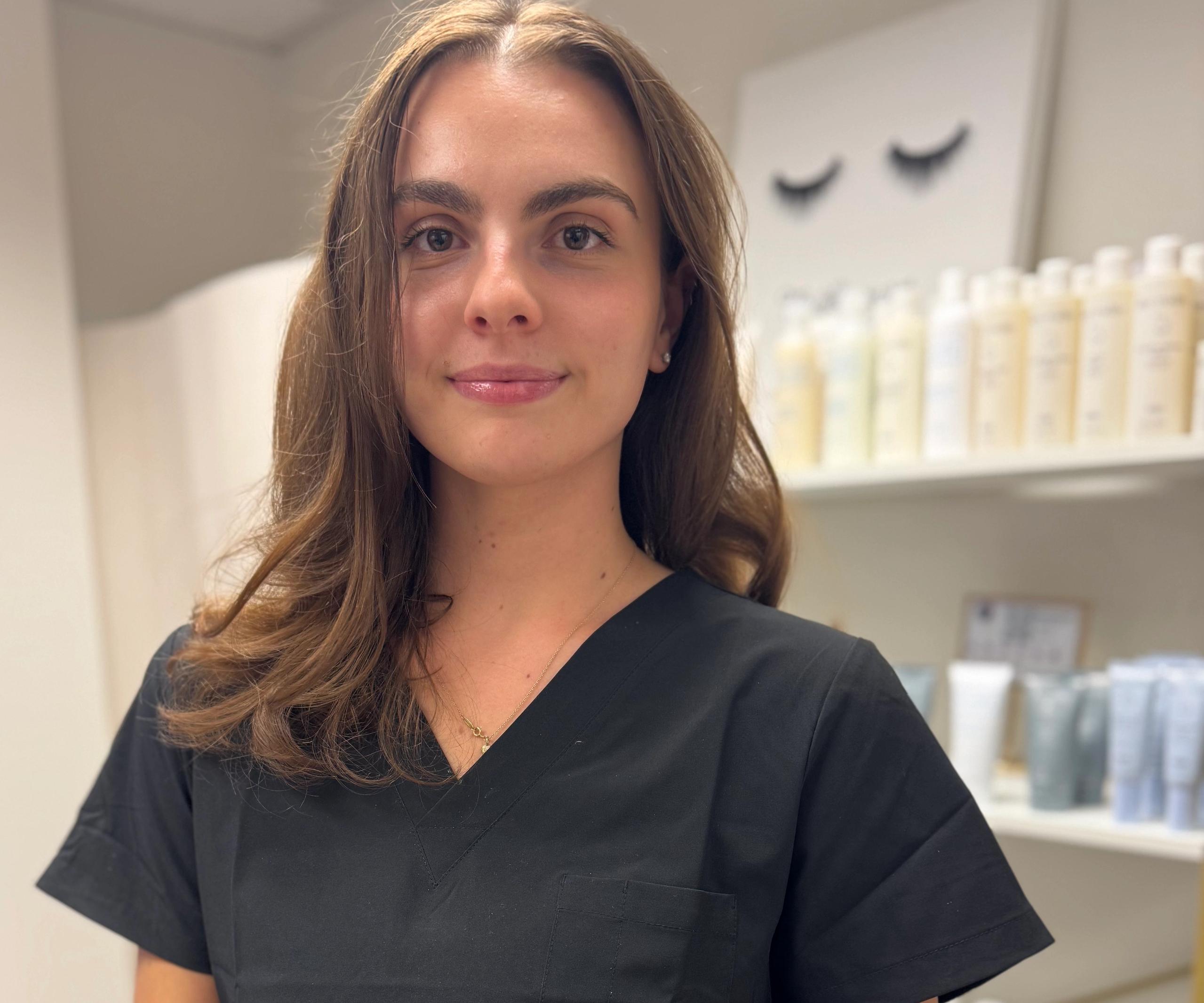 Portrait of a smiling woman with brown hair and a black headband in a spa setting