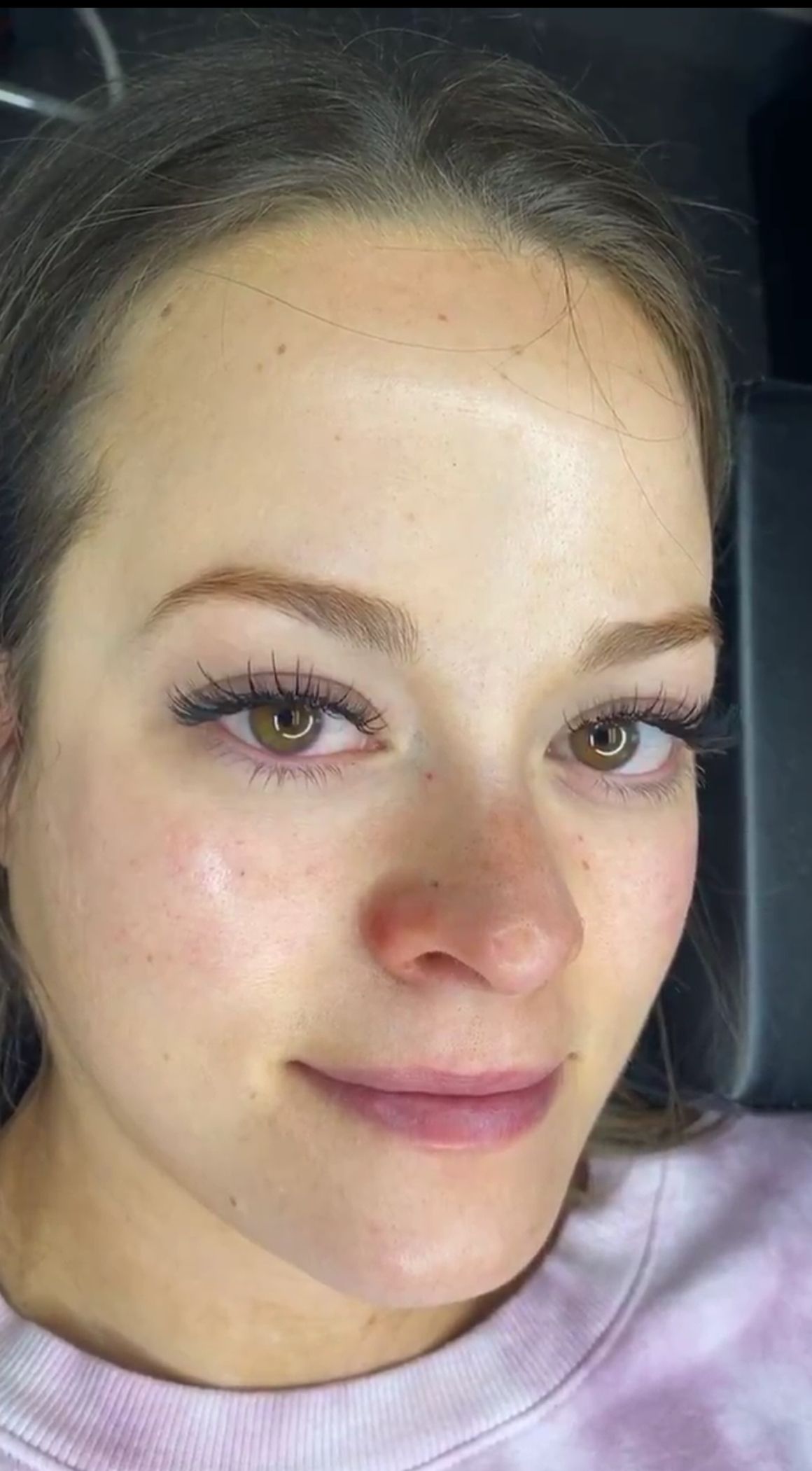 A woman with brown eyes and long, dark eyelashes smiles slightly.