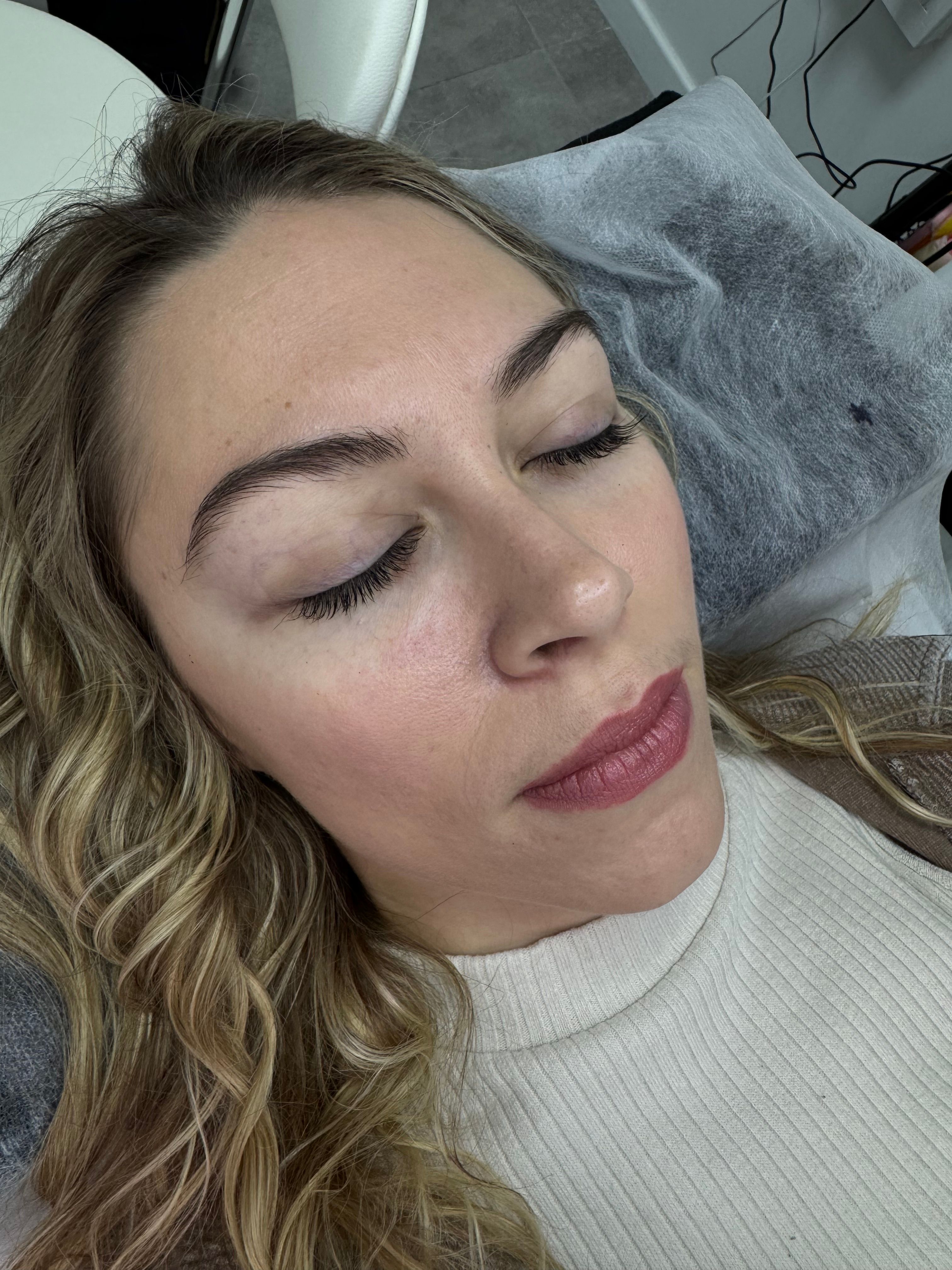 Close-up of a woman lying down with closed eyes, showing natural eyelashes and eyebrows