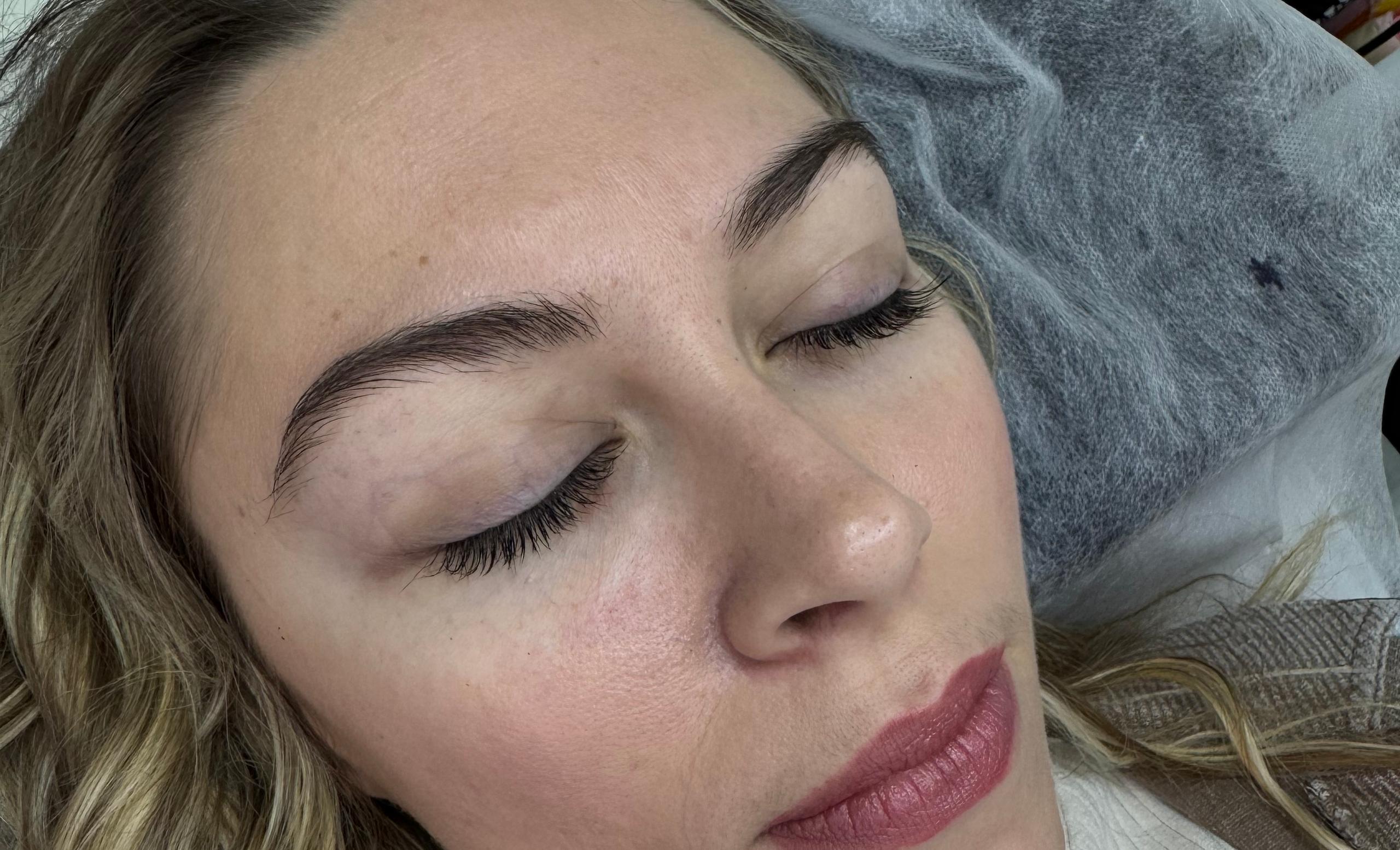 Close-up of a woman lying down with closed eyes, showing natural eyelashes and eyebrows
