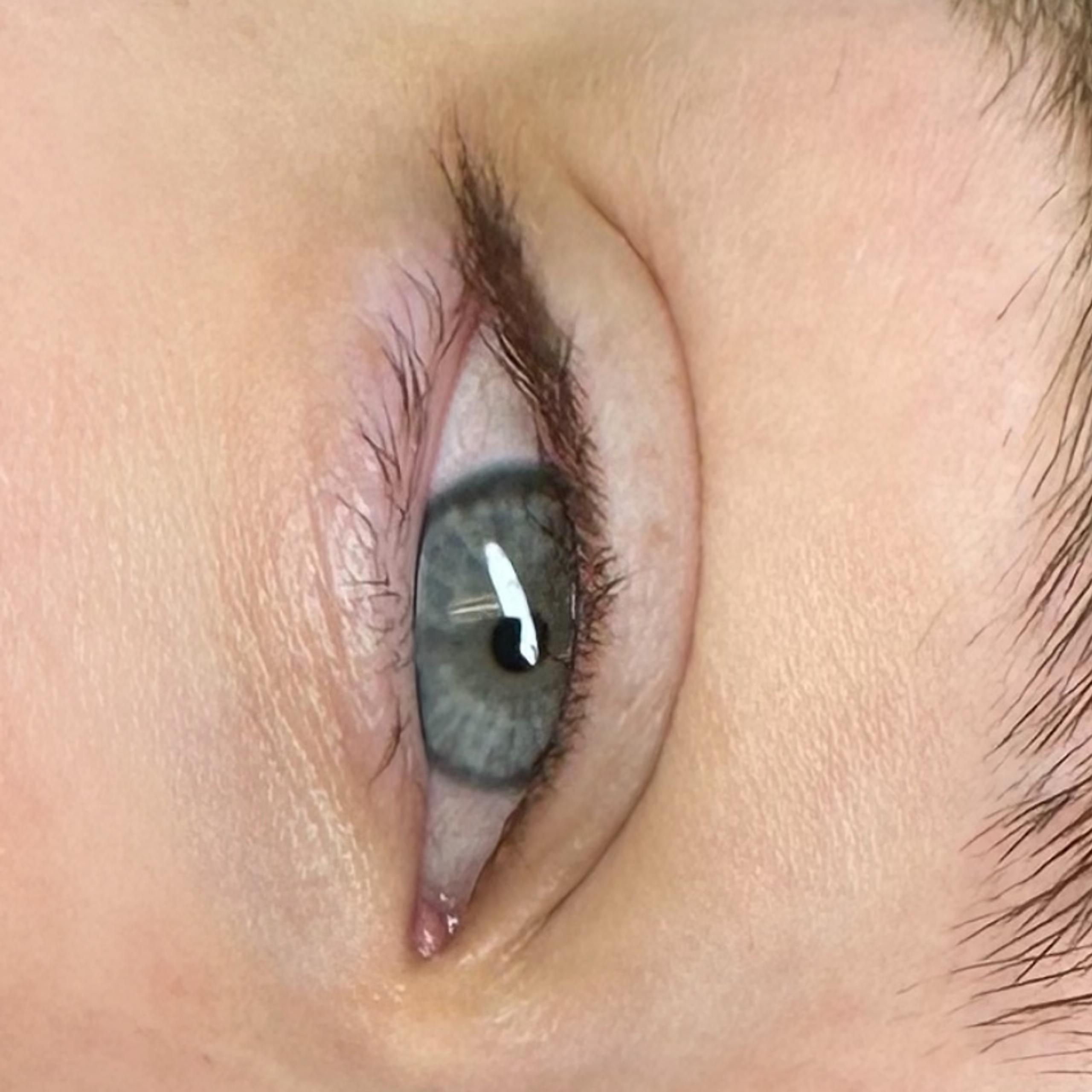 Close-up of a person's two blue-grey eyes and brown eyebrows.