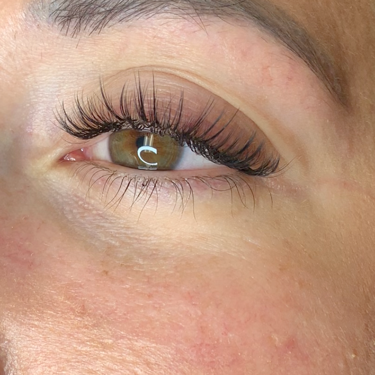 Close-up of an eye with long, dark, voluminous eyelash extensions.