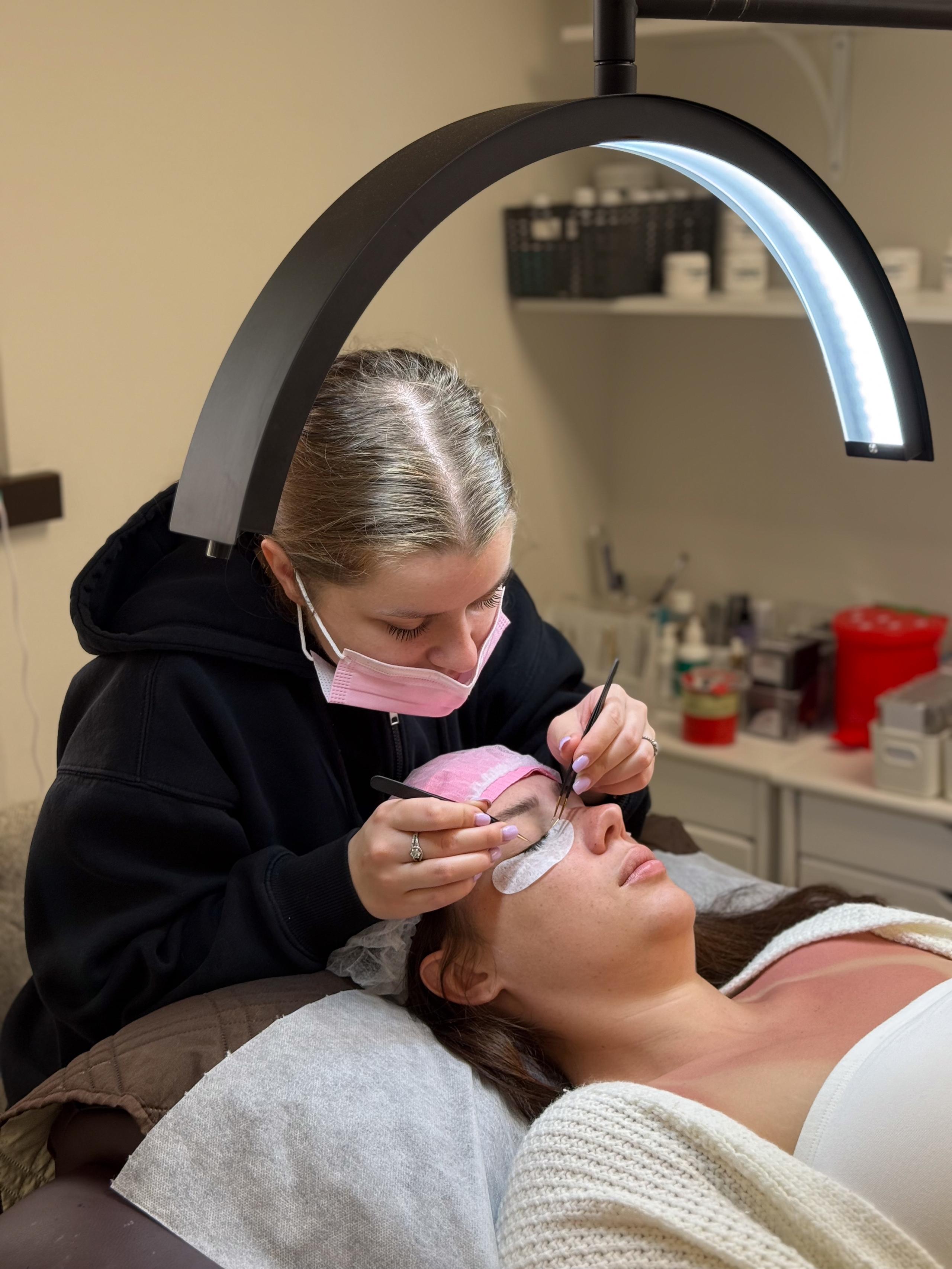 Lash artist working on a client's lashes under a ring light at Beauty Republic in Woburn.