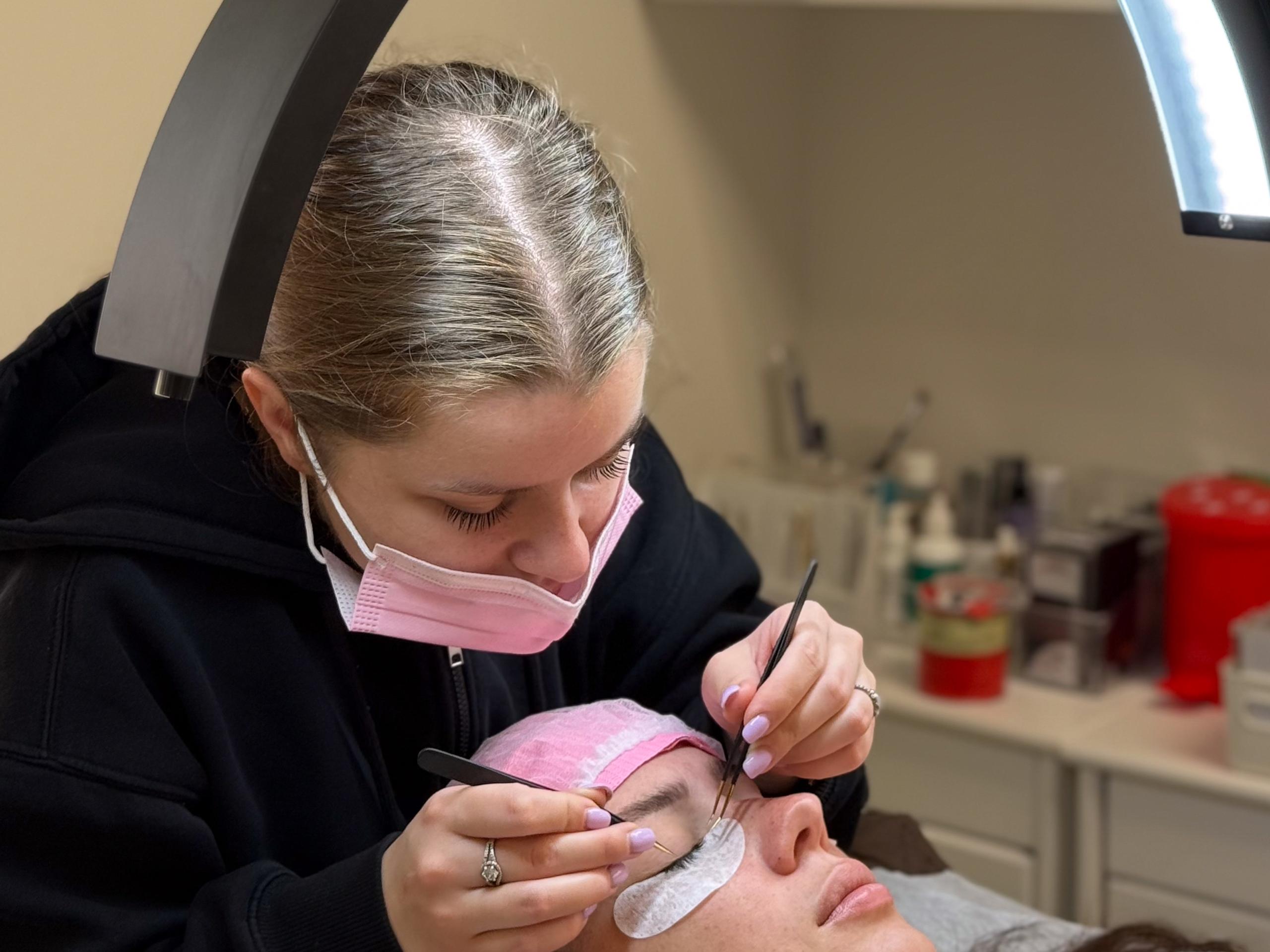 Lash artist working on a client's lashes under a ring light at Beauty Republic in Woburn.