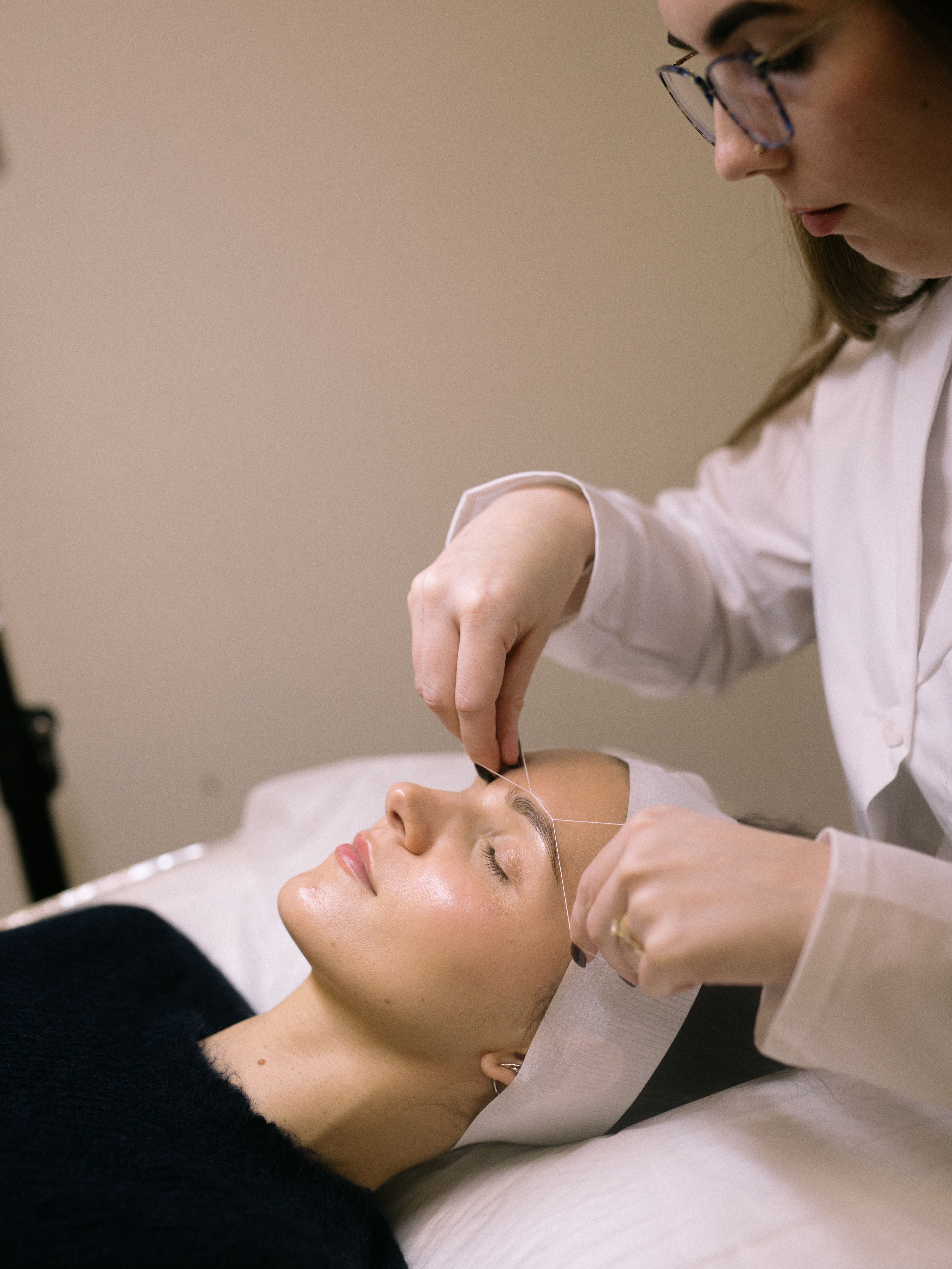 A woman getting her eyebrows threaded.