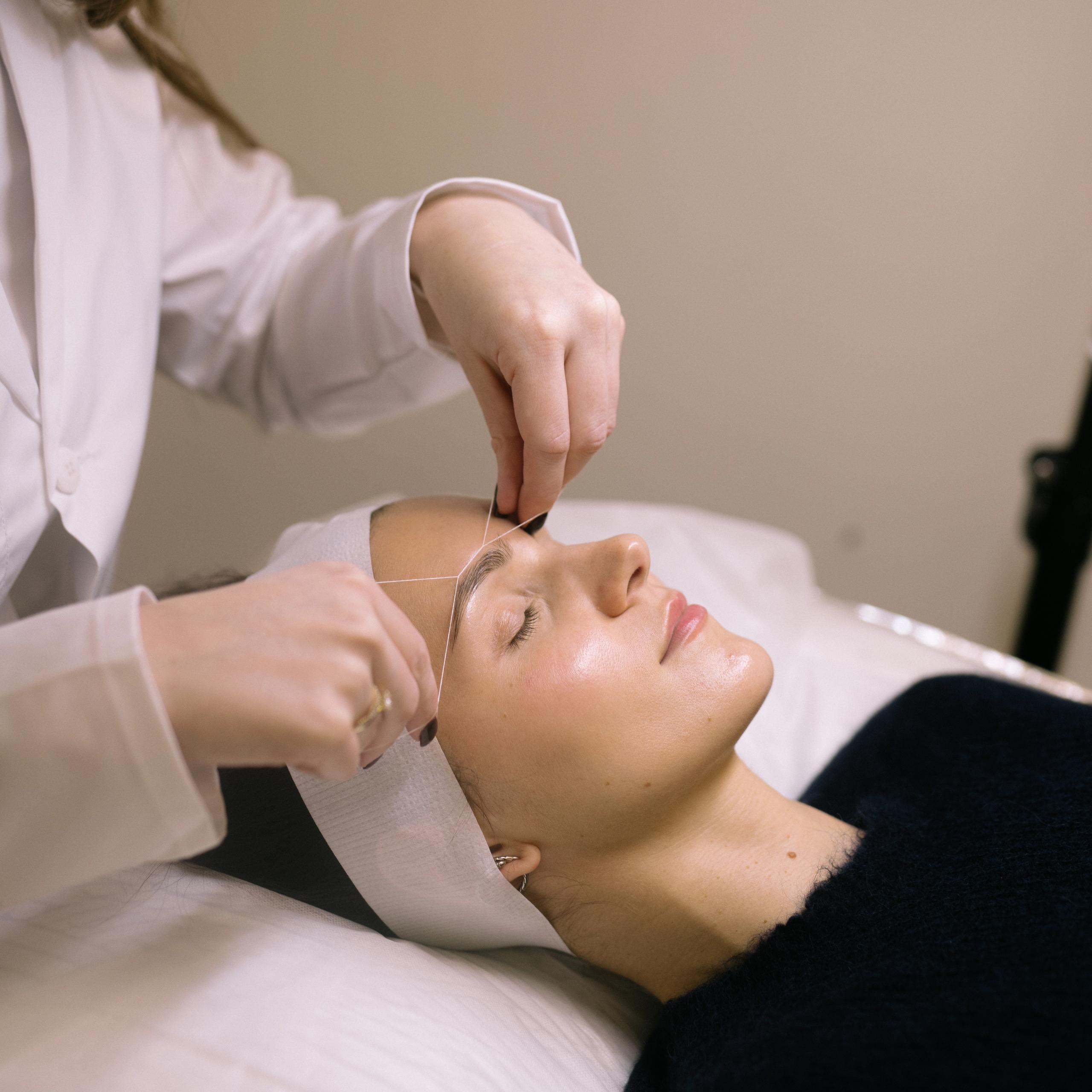 A woman getting her eyebrows threaded.