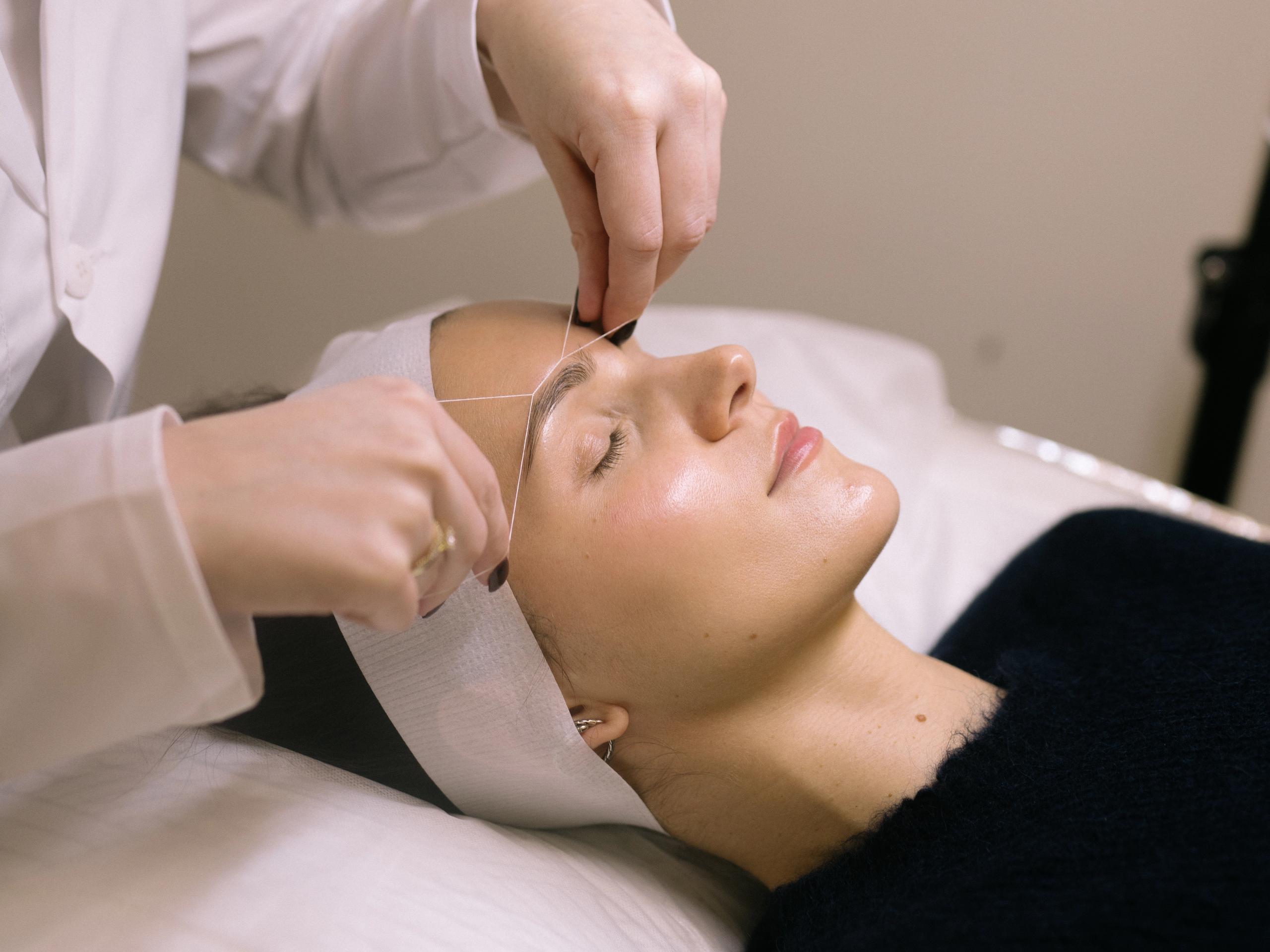 A woman getting her eyebrows threaded.