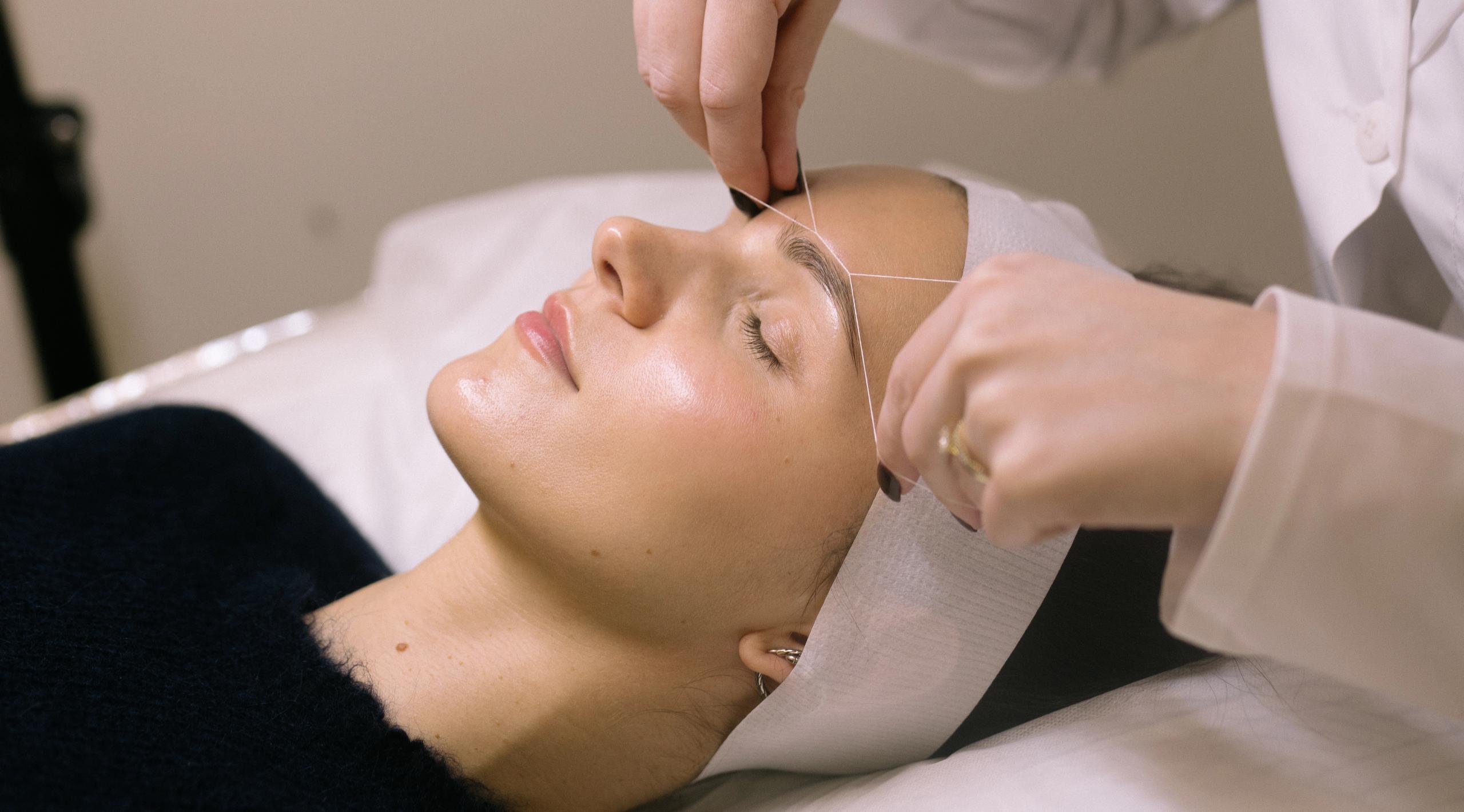 Woman getting her eyebrows threaded.
