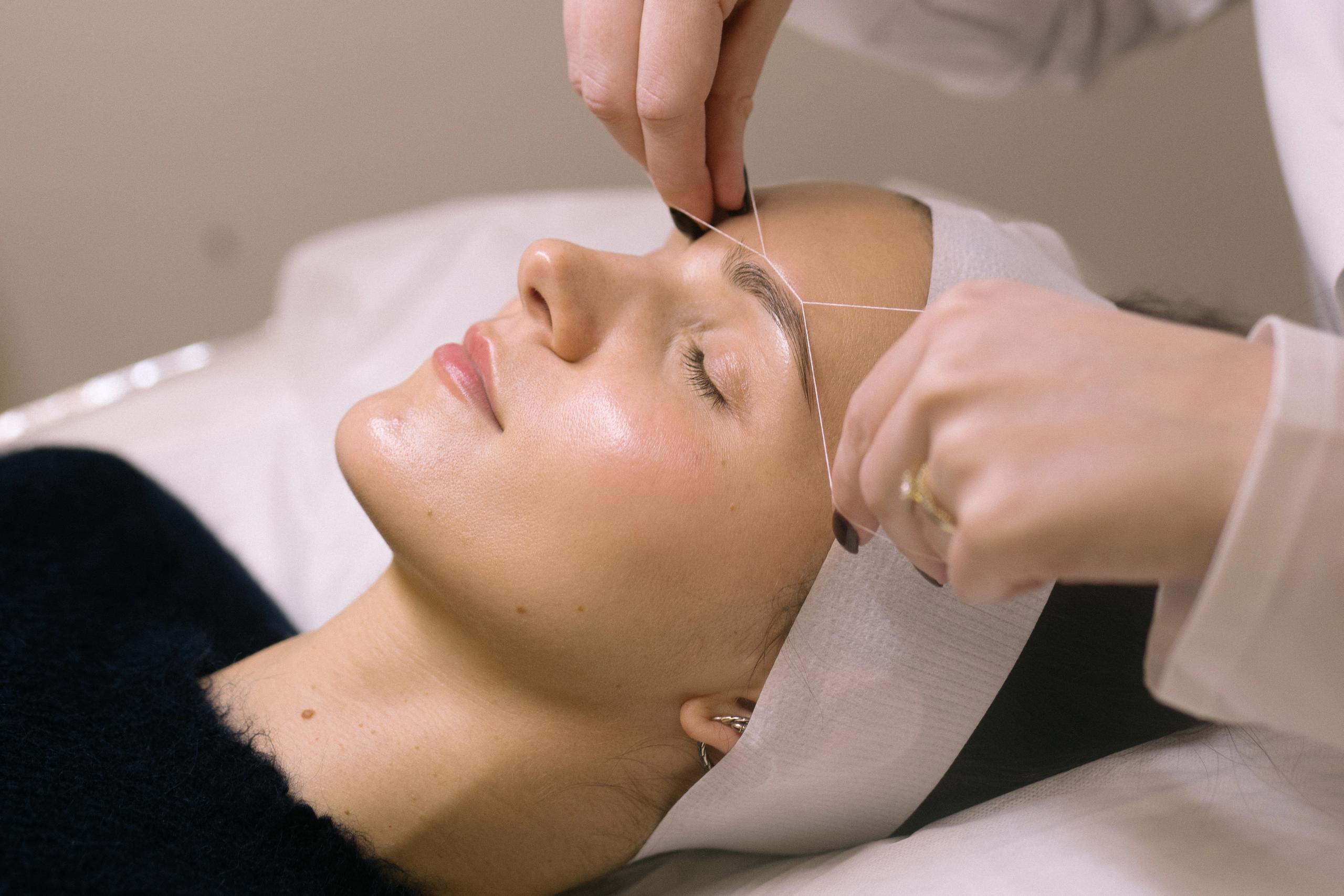 Woman getting her eyebrows threaded.