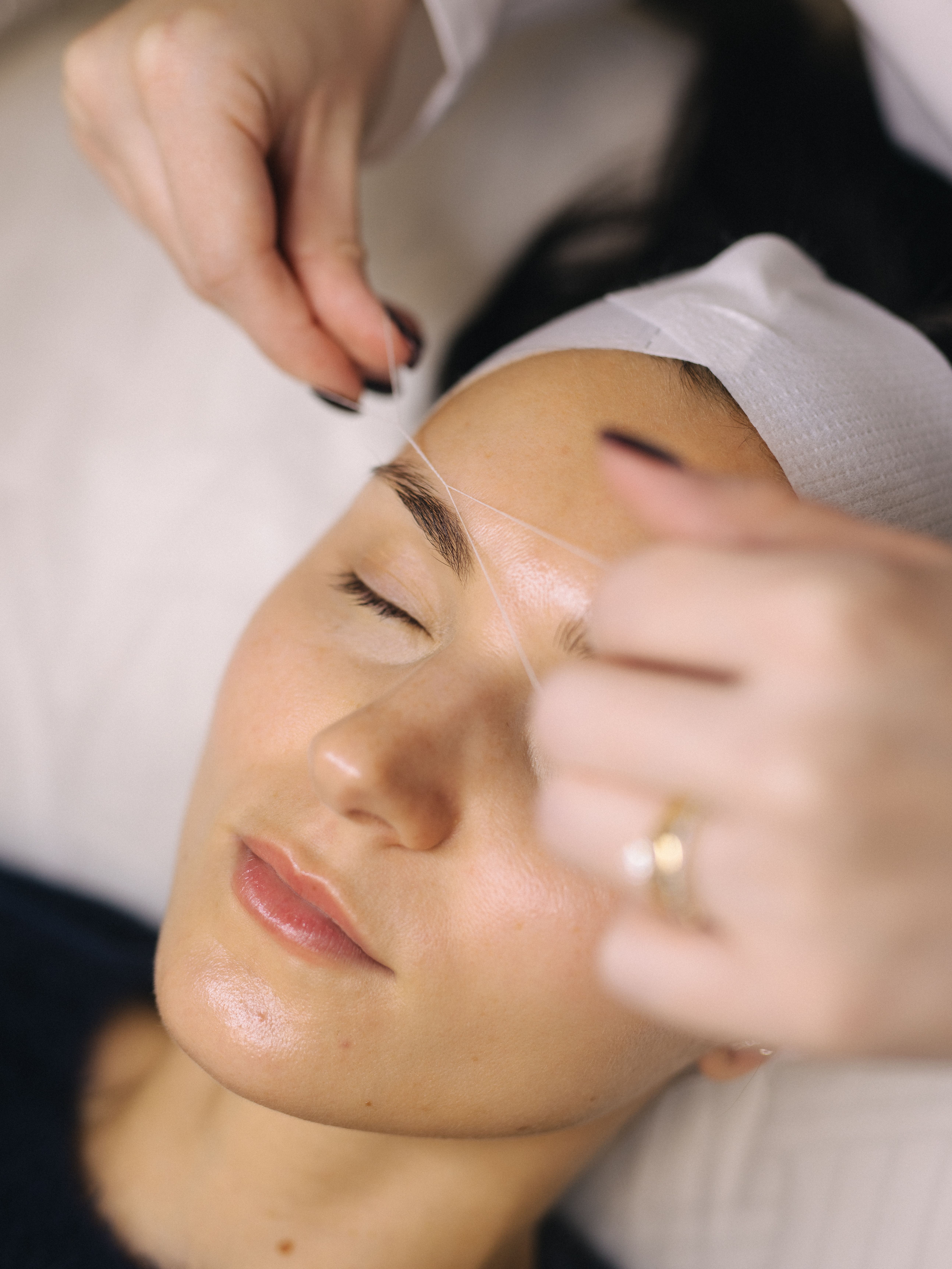 Close-up of hands threading an eyebrow.