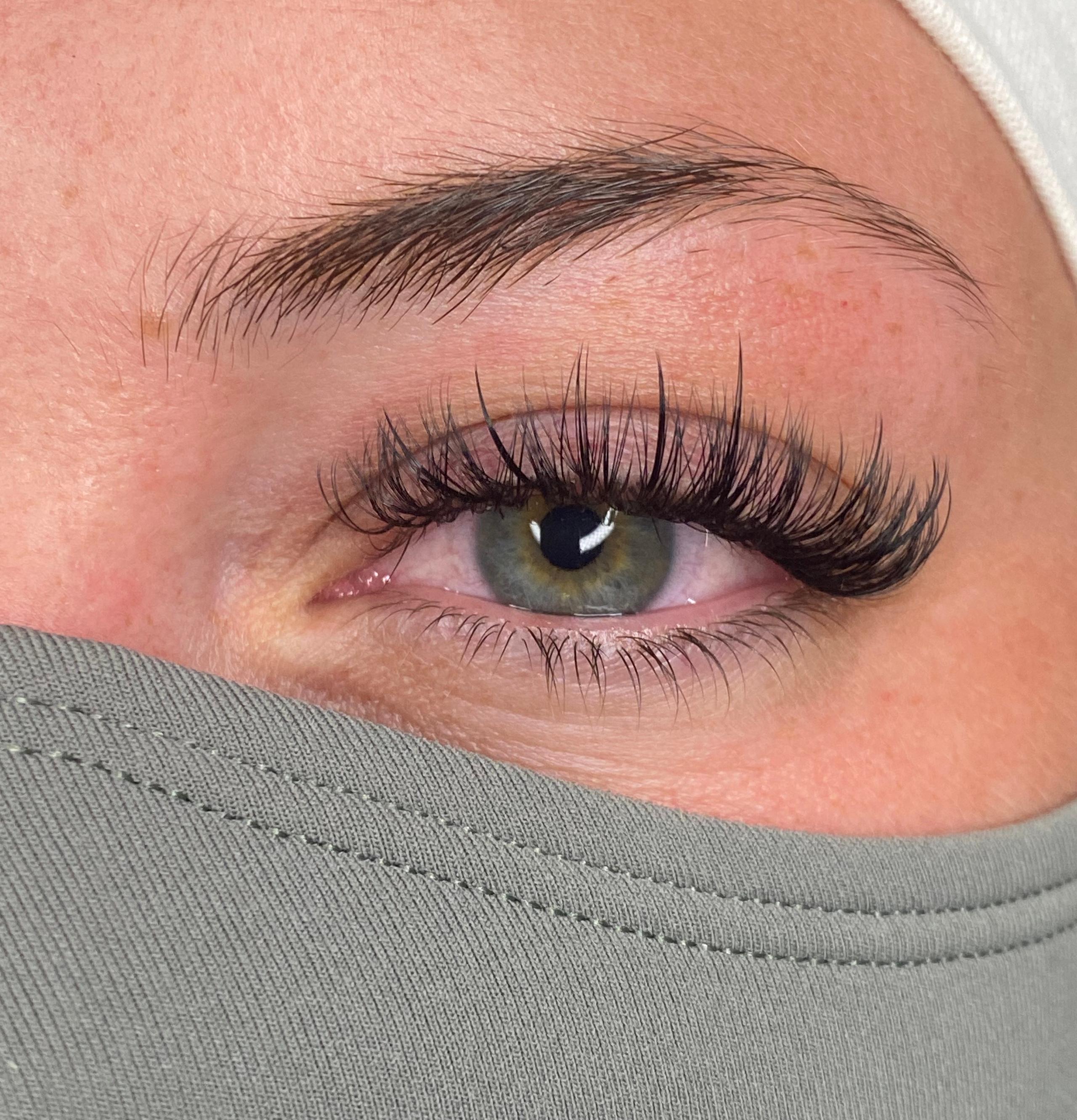 Close-up of a green eye with voluminous eyelash extensions with wispy spikes