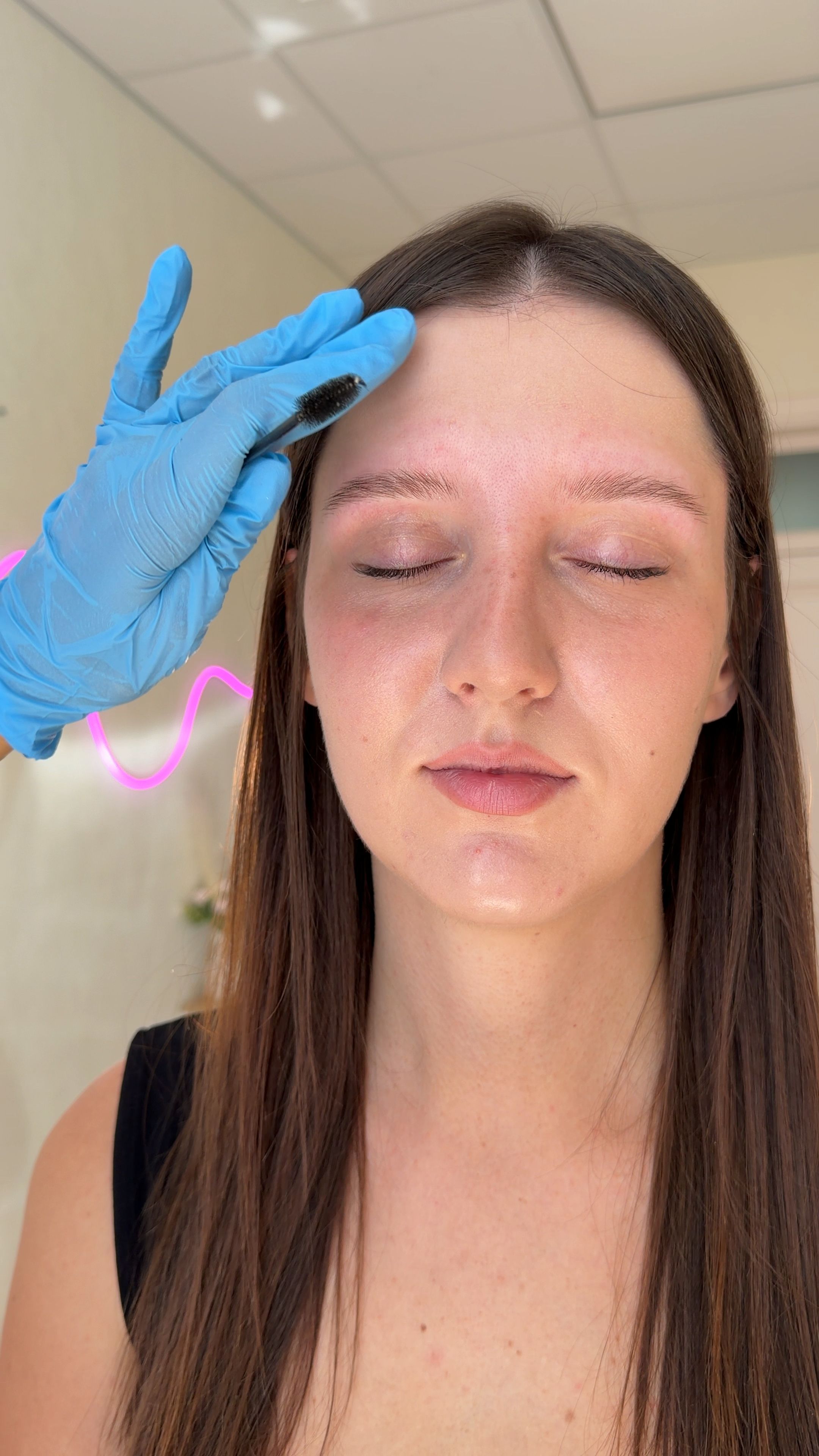 Brow specialist brushes a client's natural eyebrows during the consultation.