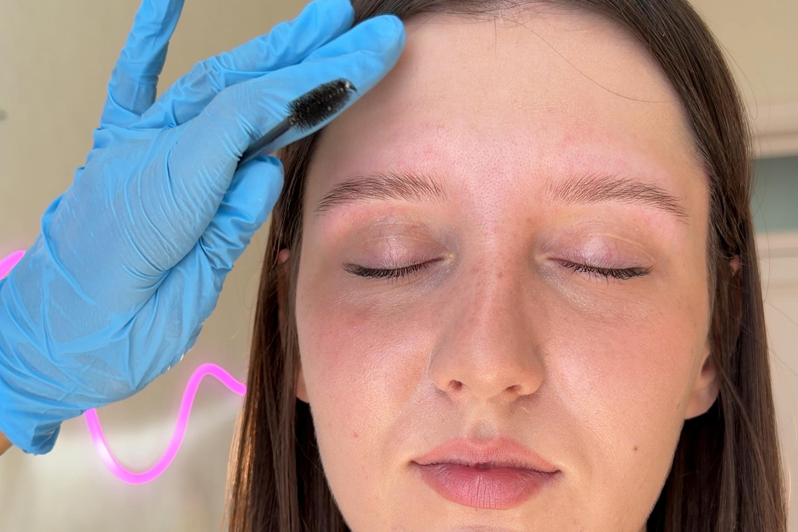 Brow specialist brushes a client's natural eyebrows during the consultation.