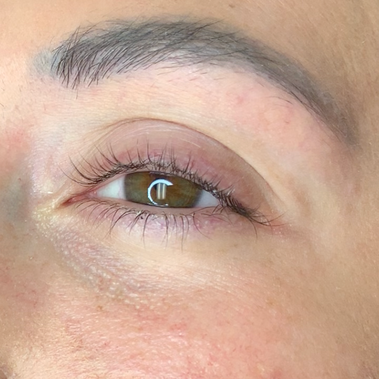 Close-up of a brown eye with upward-curled eyelashes.