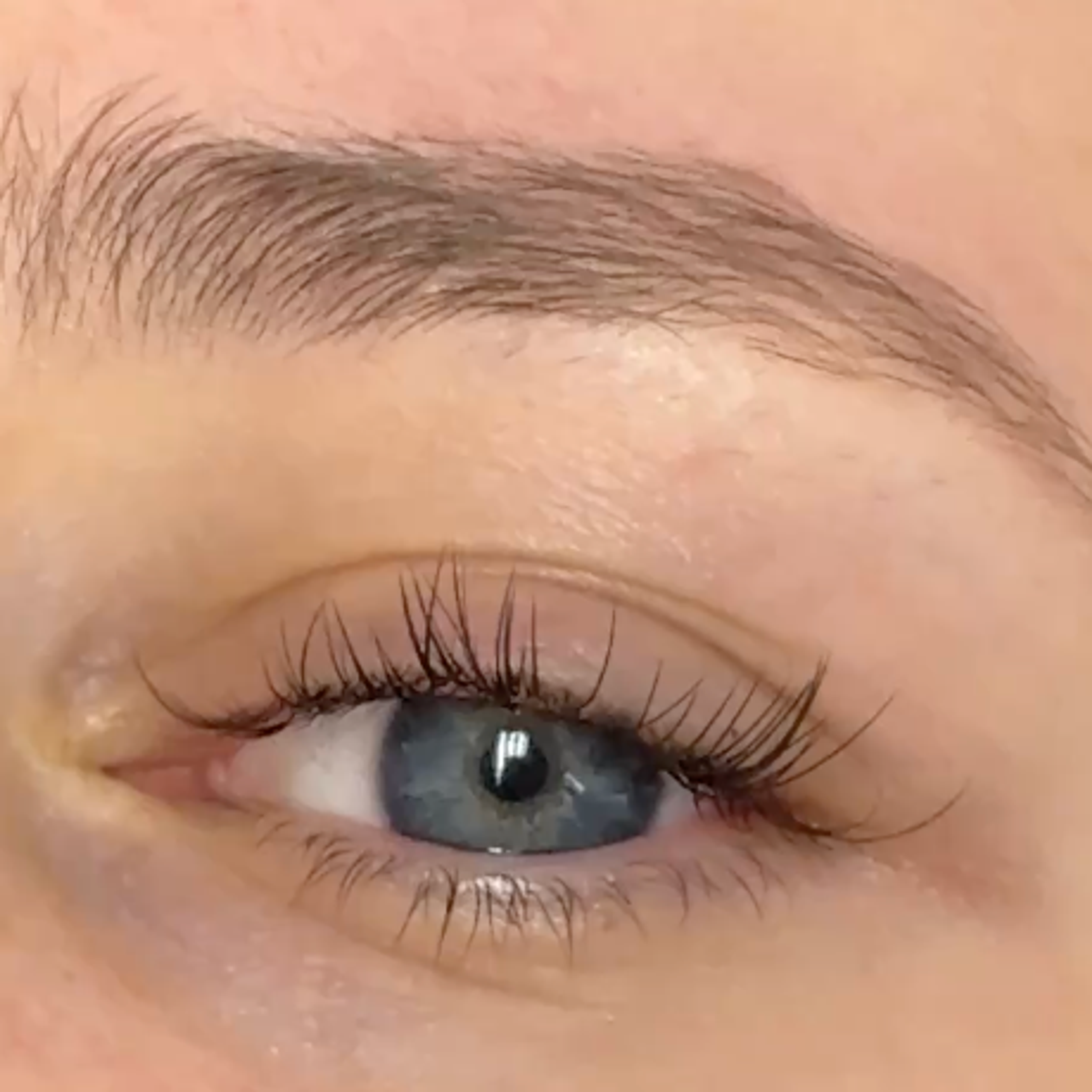 Close-up of a person's blue eye with eyelashes extensions with gaps