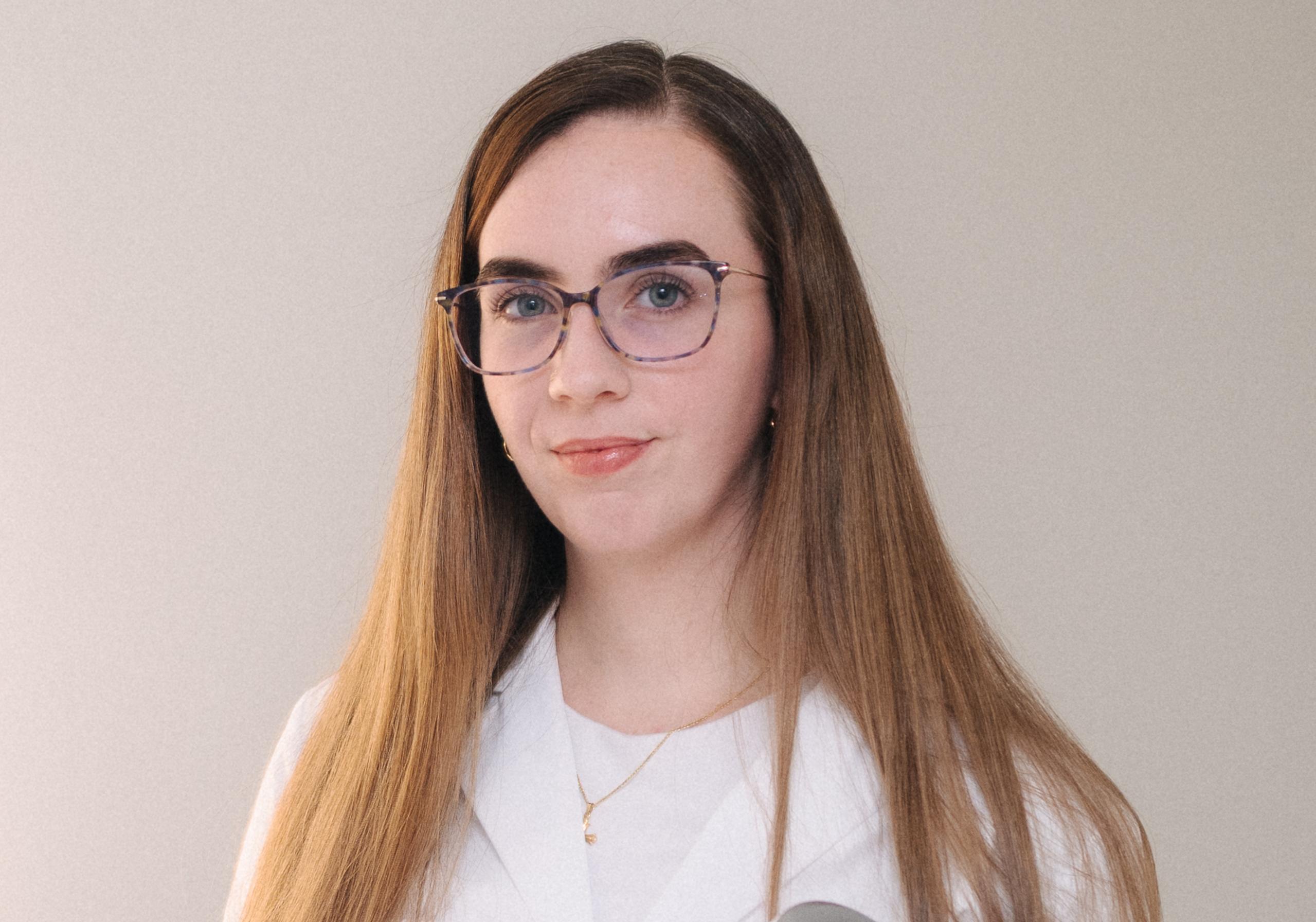 A woman in a white lab coat holds a device with blue lights, standing next to a white ENDOLUXX aesthetic machine.