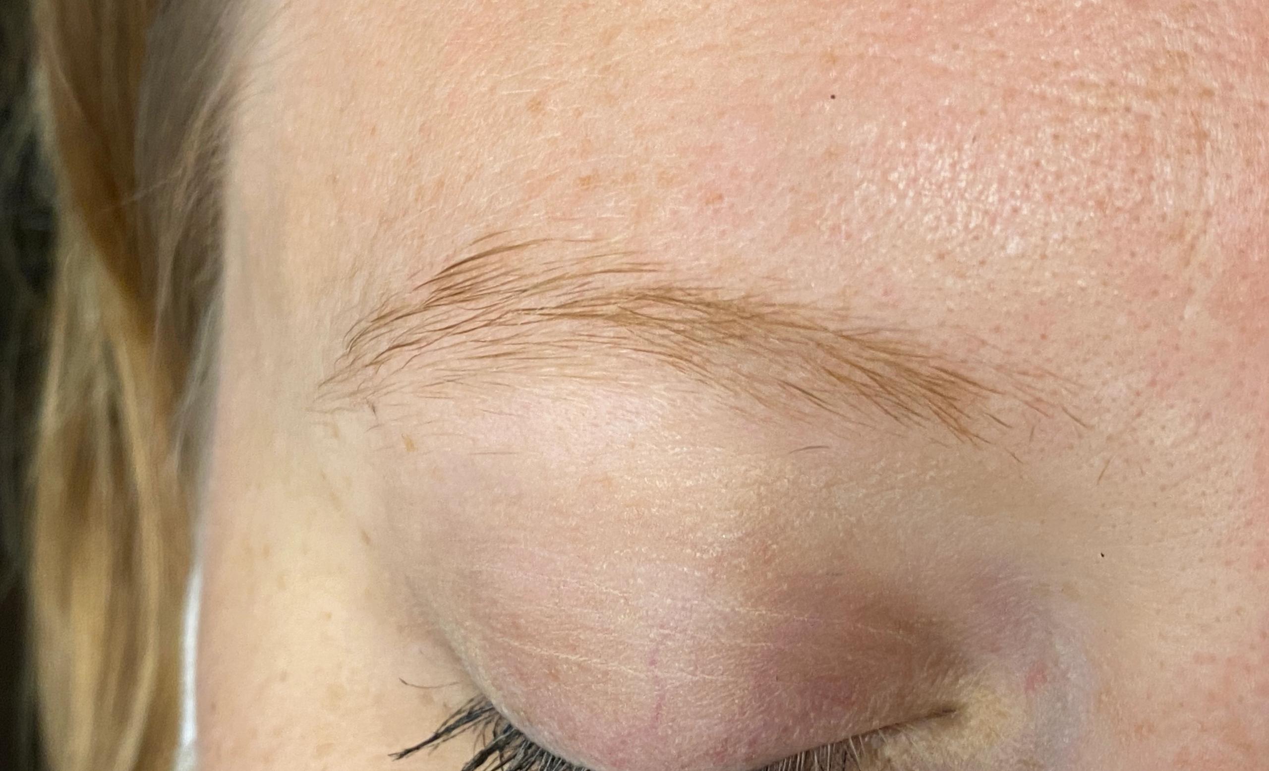 A close-up of a closed eye with a light brown eyebrow and dark eyelashes.