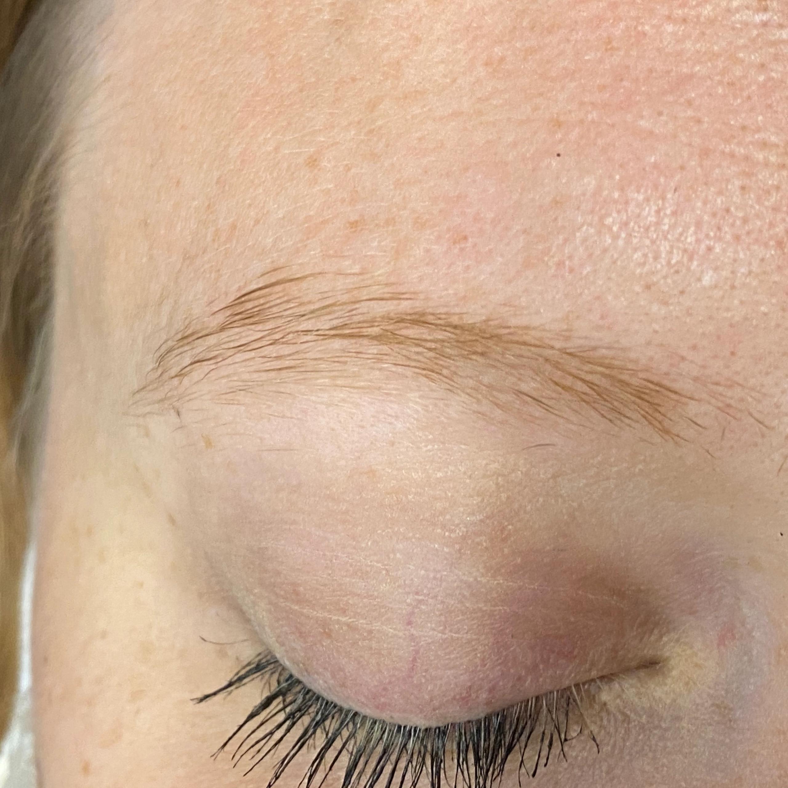 Close-up of a light-colored eyebrow, closed eyelid with mascara, and light skin.