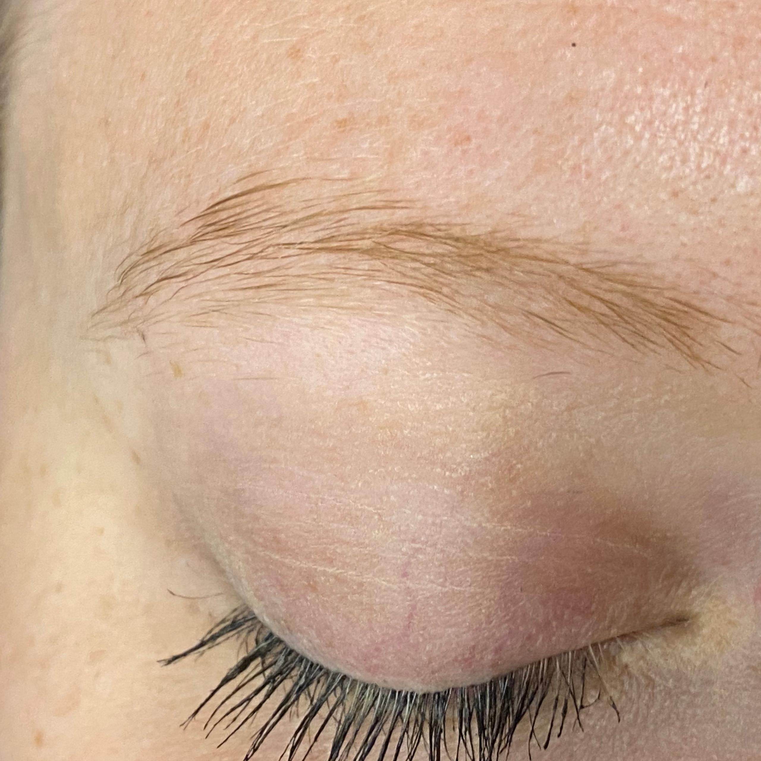 Close-up of a light-colored eyebrow, closed eyelid with mascara, and light skin.