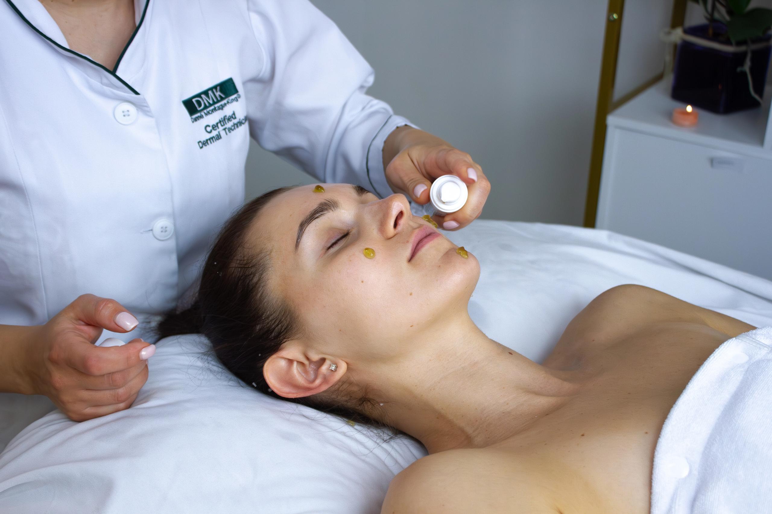 A technician applies product to a woman's face