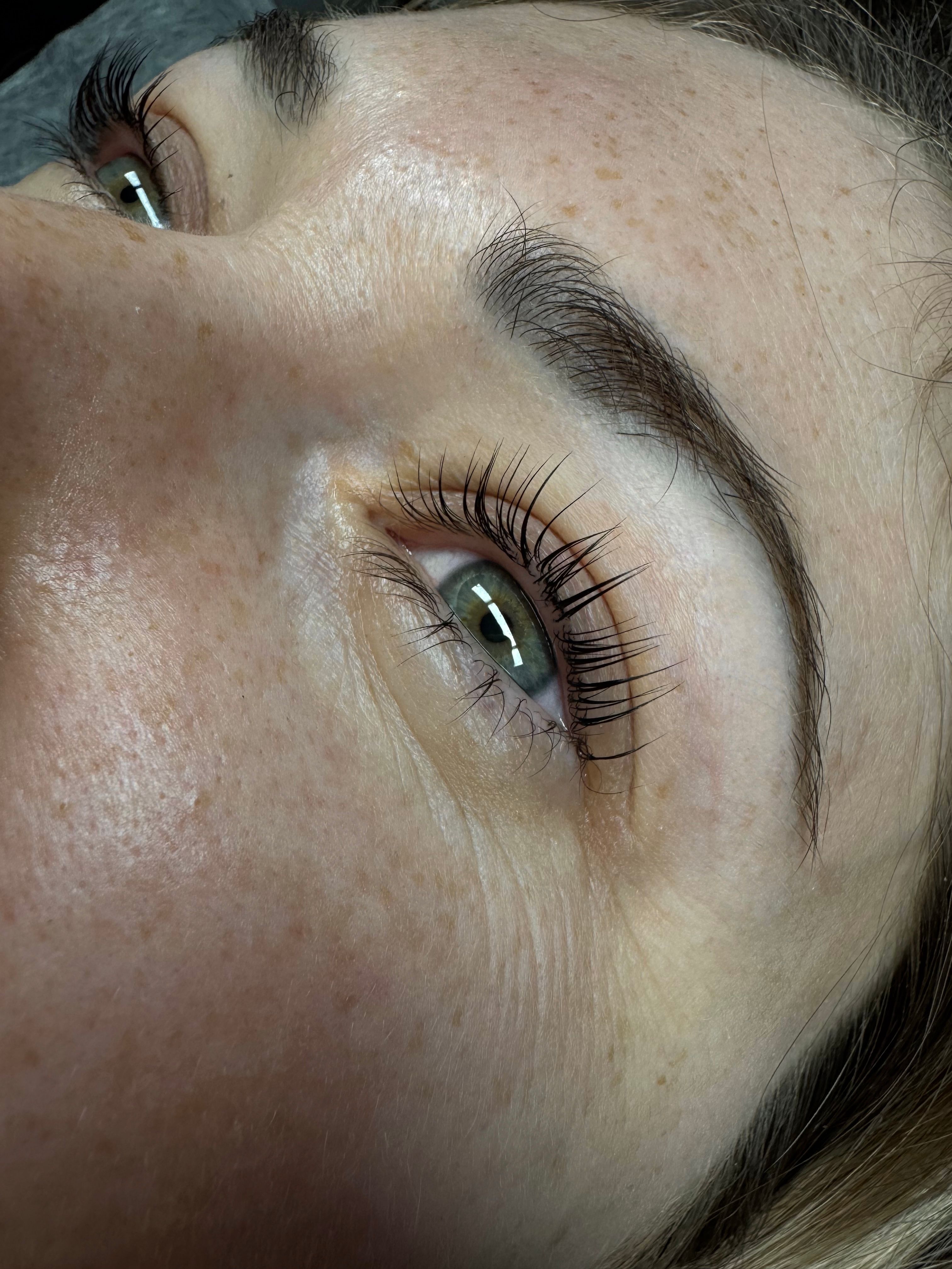 Close-up of a person's two green-grey eyes and brown eyebrows.