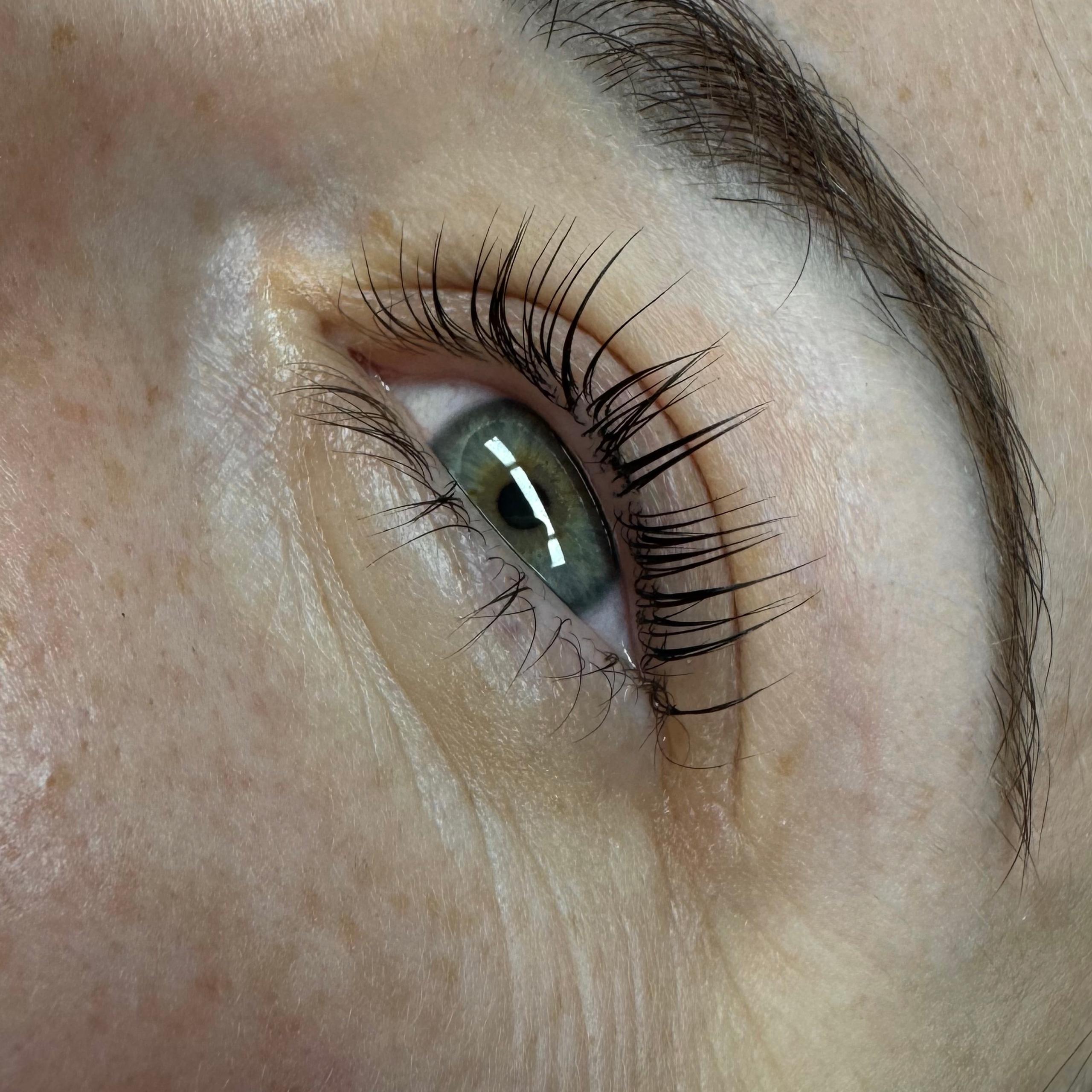 Close-up of a person's two green-grey eyes and brown eyebrows.