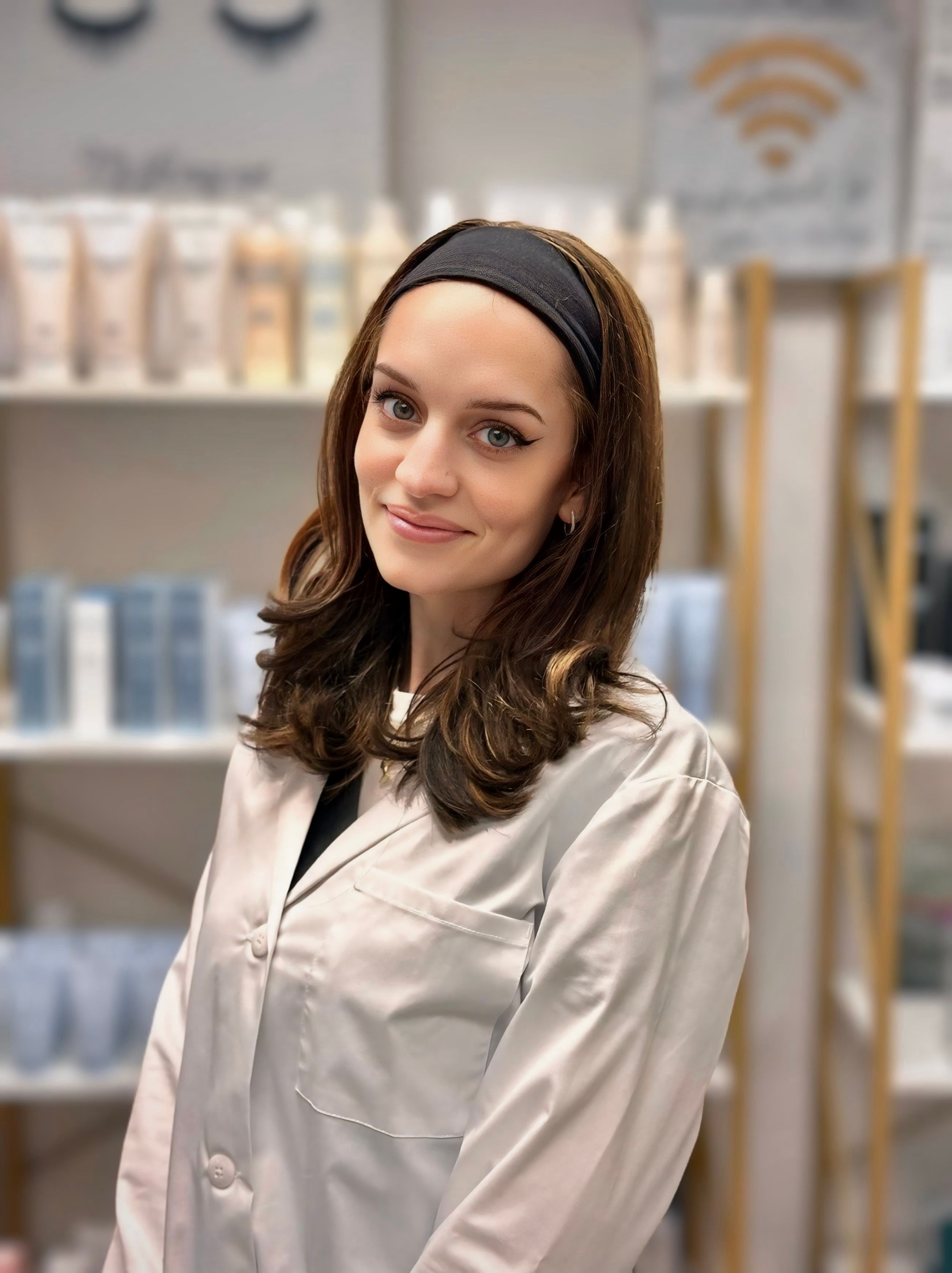 A smiling woman in a white coat with a bandage on her head.