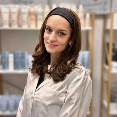 A smiling woman in a white coat with a bandage on her head.