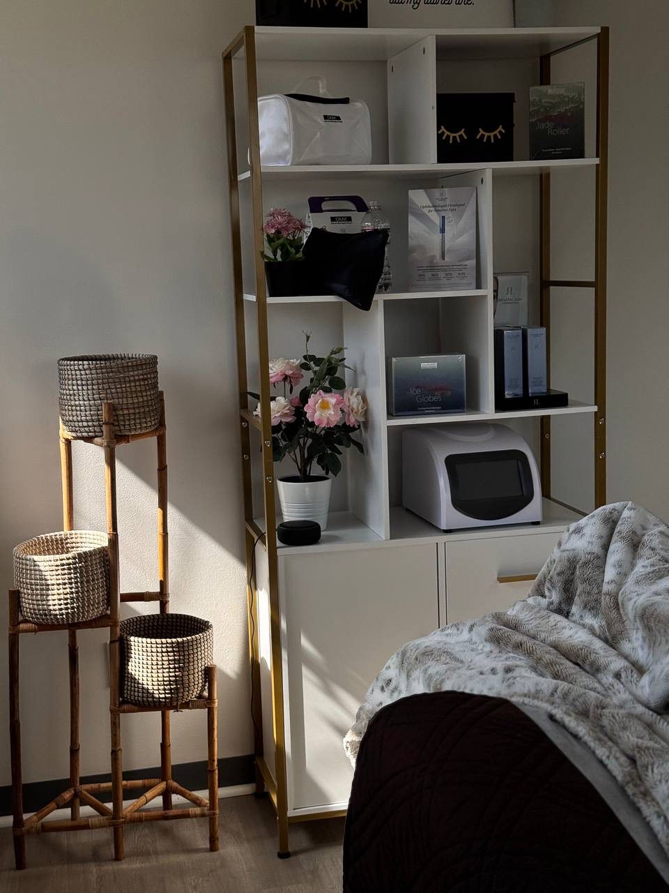 Sunlit Beauty Republic treatment space with a blanket-covered chair, display shelves, and woven basket stands.