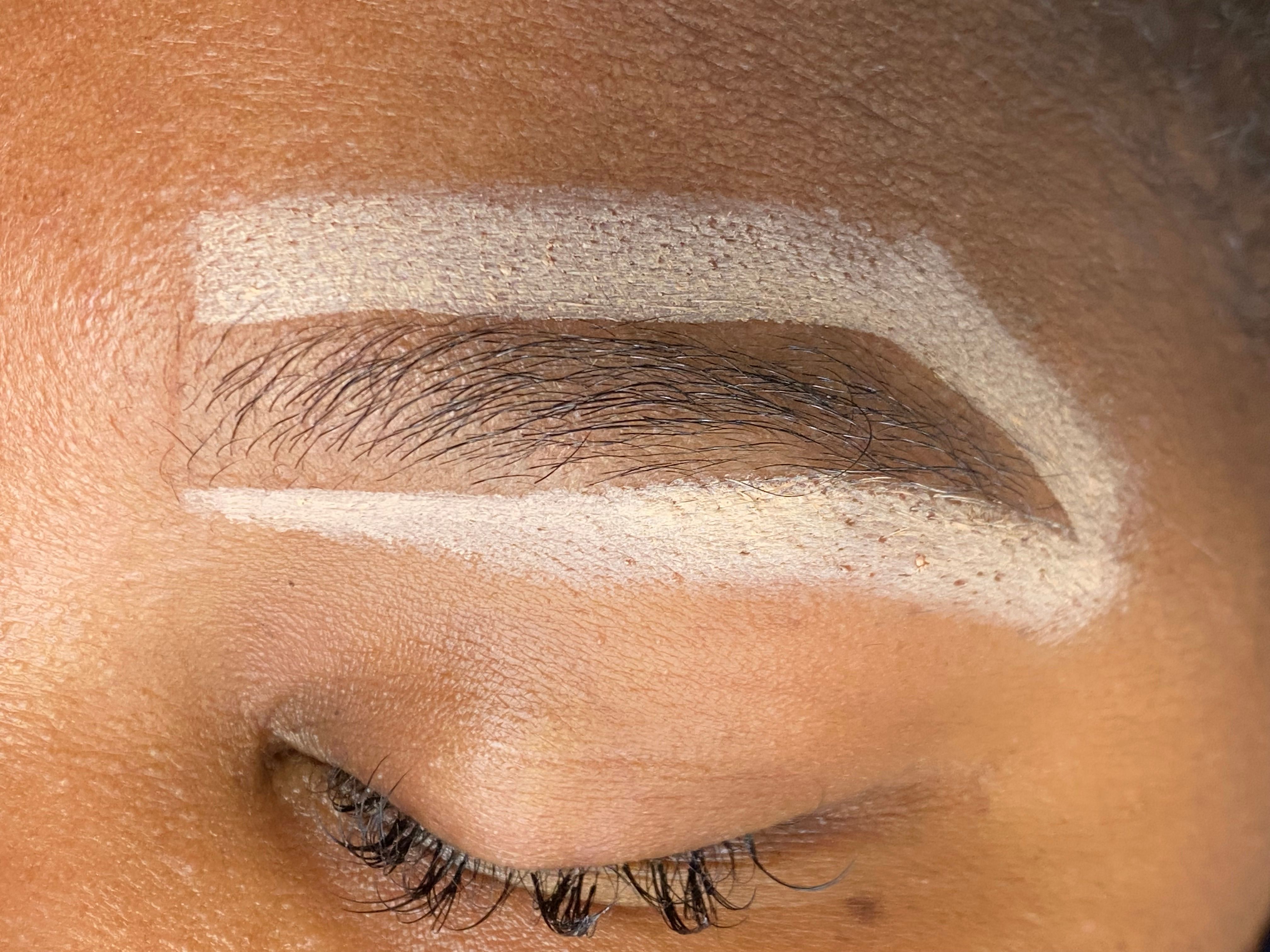 Close-up of a closed eye with the eyebrow sharply outlined by a light-colored makeup.