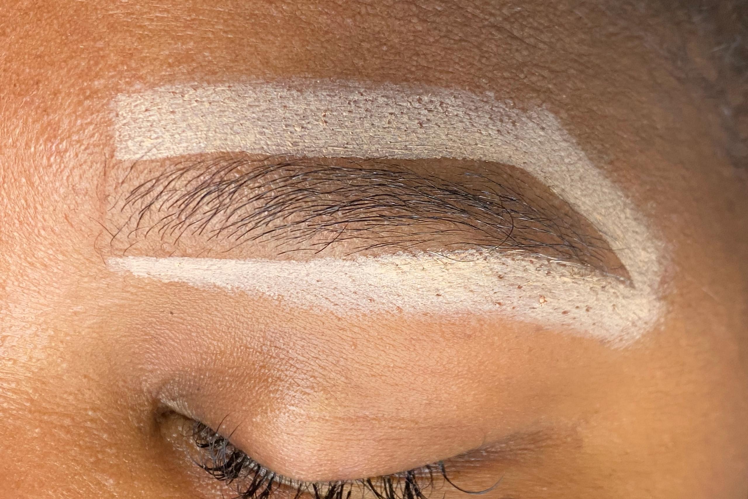Close-up of a closed eye with the eyebrow sharply outlined by a light-colored makeup.