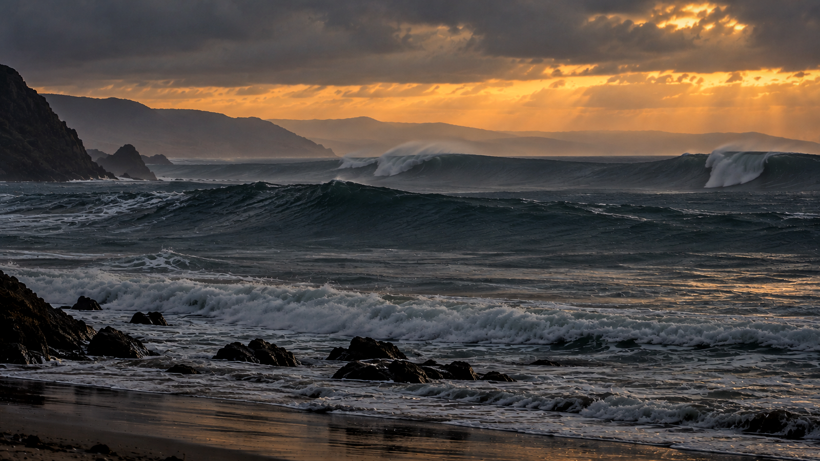 Grandes olas rompen junto a una costa rocosa bajo nubes iluminadas por el sol del atardecer.
