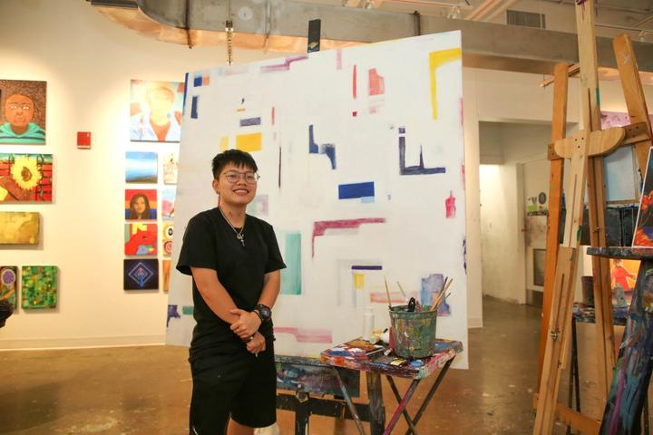 Teen artist proudly posing with painting