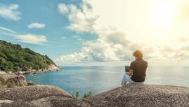 here is how to plan a digital nomad lifestyle.jpg A man working on a laptop remotely in front of the sea