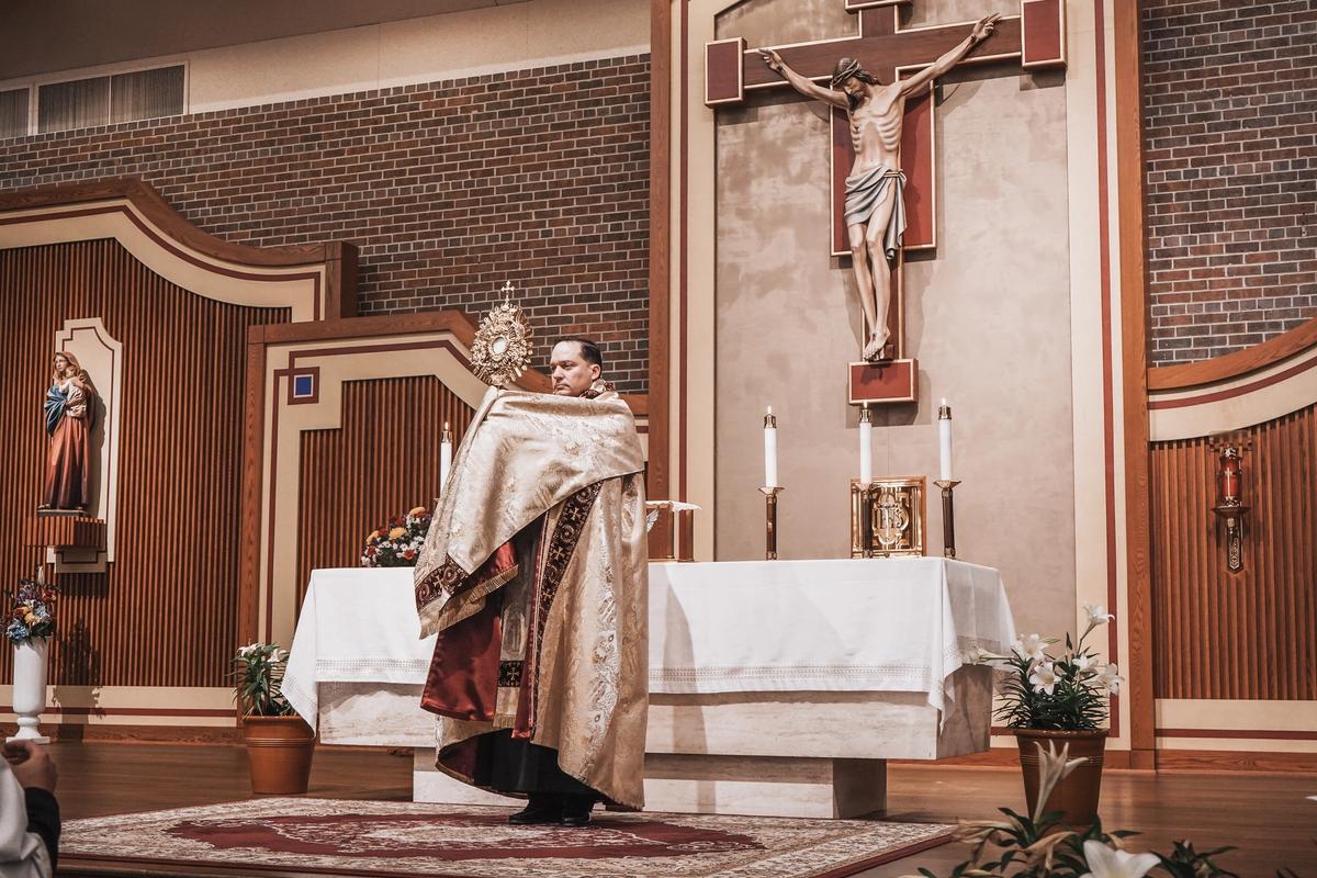 Sacerdote sosteniendo una custodia ante el altar