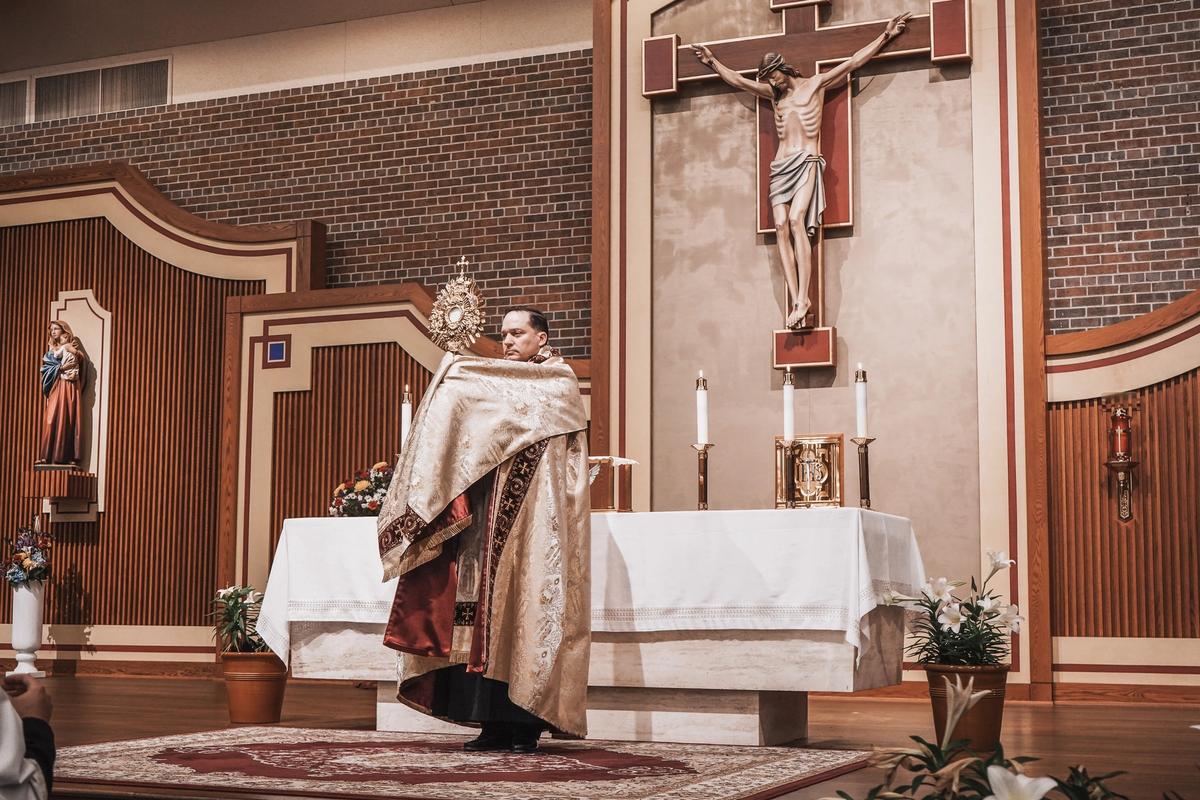 Sacerdote sosteniendo una custodia ante el altar