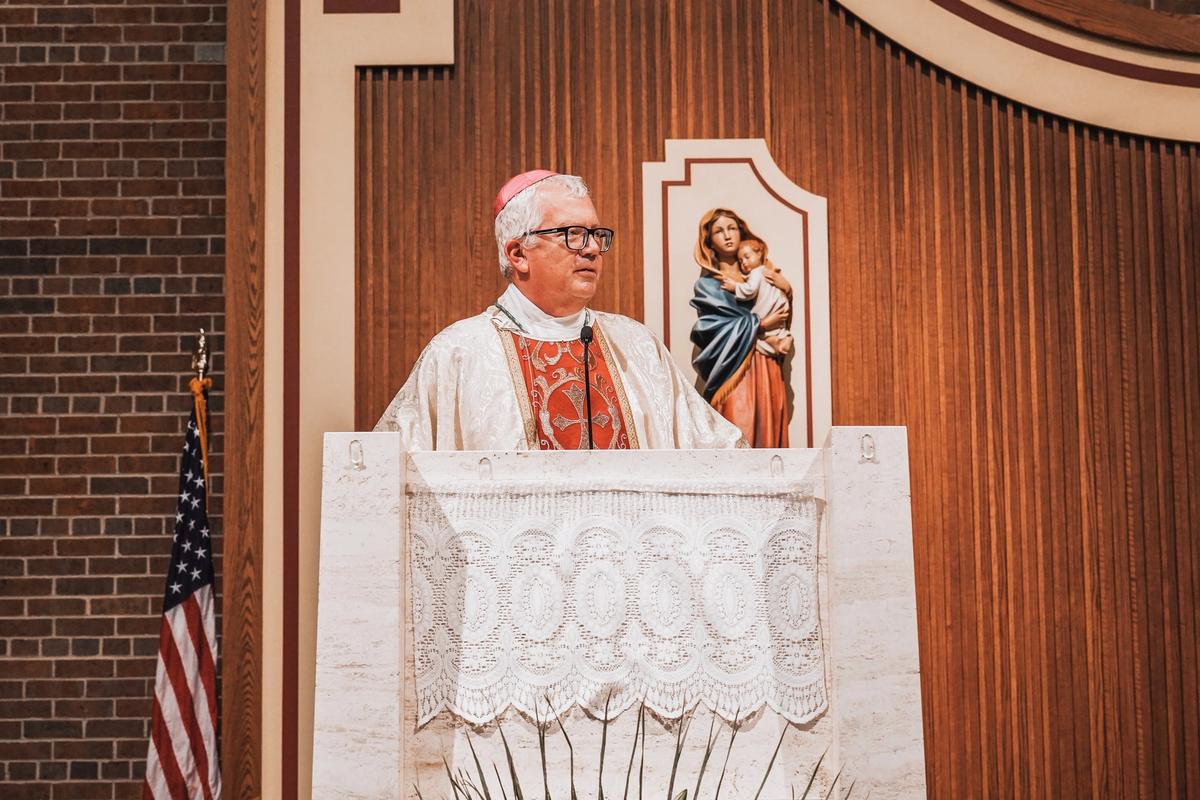 Bishop preaching at the ambo beside an image of Mary and Jesus