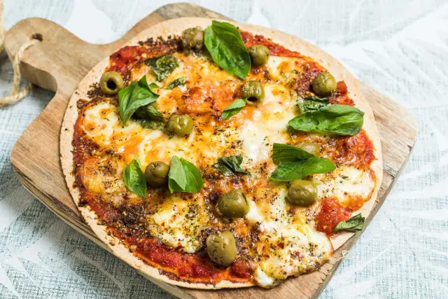 Pizza Margherita on a tortilla base with lots of cheese and olives