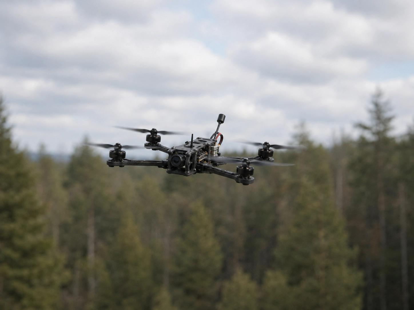 Small FPV racing drone in flight above a pine forest