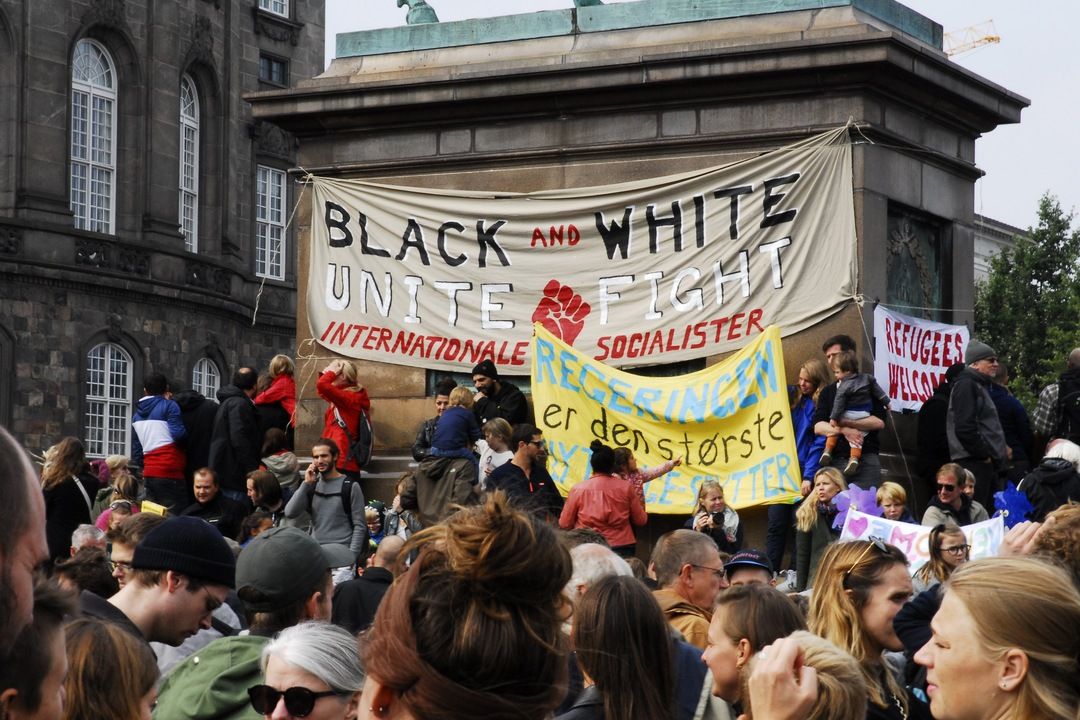 Demonstrators below a banner reading Black and White Unite and Fight