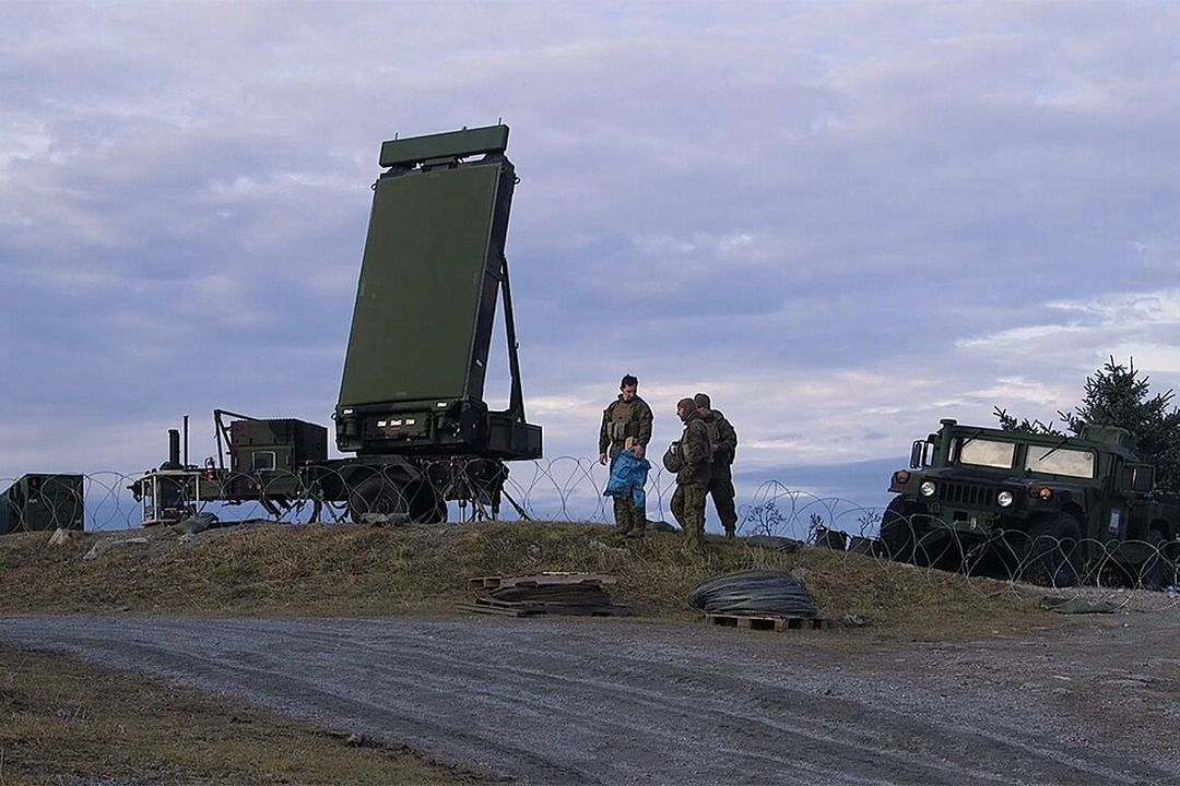 Mobile military radar array deployed on a hilltop with soldiers and Humvee