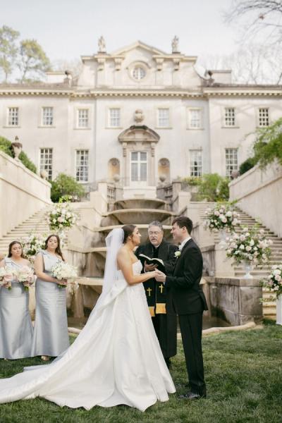 Ceremony in front of the cascading fountains and stone staircase at the Swan House in Atlanta, with blush and white arrangements flanking the couple