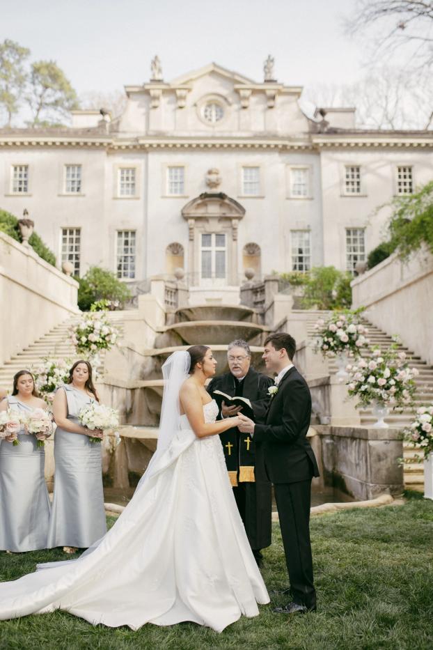Ceremony in front of the cascading fountains and stone staircase at the Swan House in Atlanta, with blush and white arrangements flanking the couple