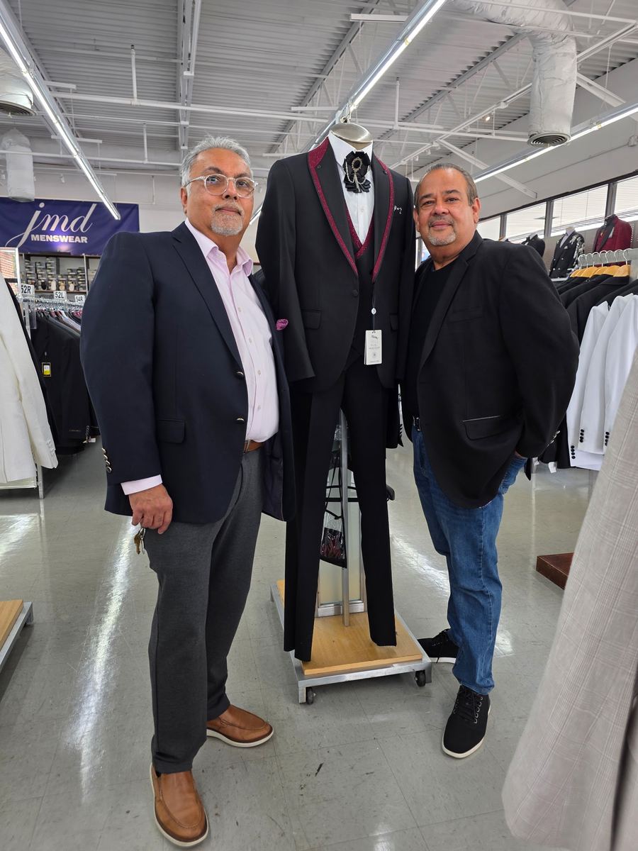 Two JMD Menswear team members standing beside a formalwear mannequin inside the Conyers showroom.